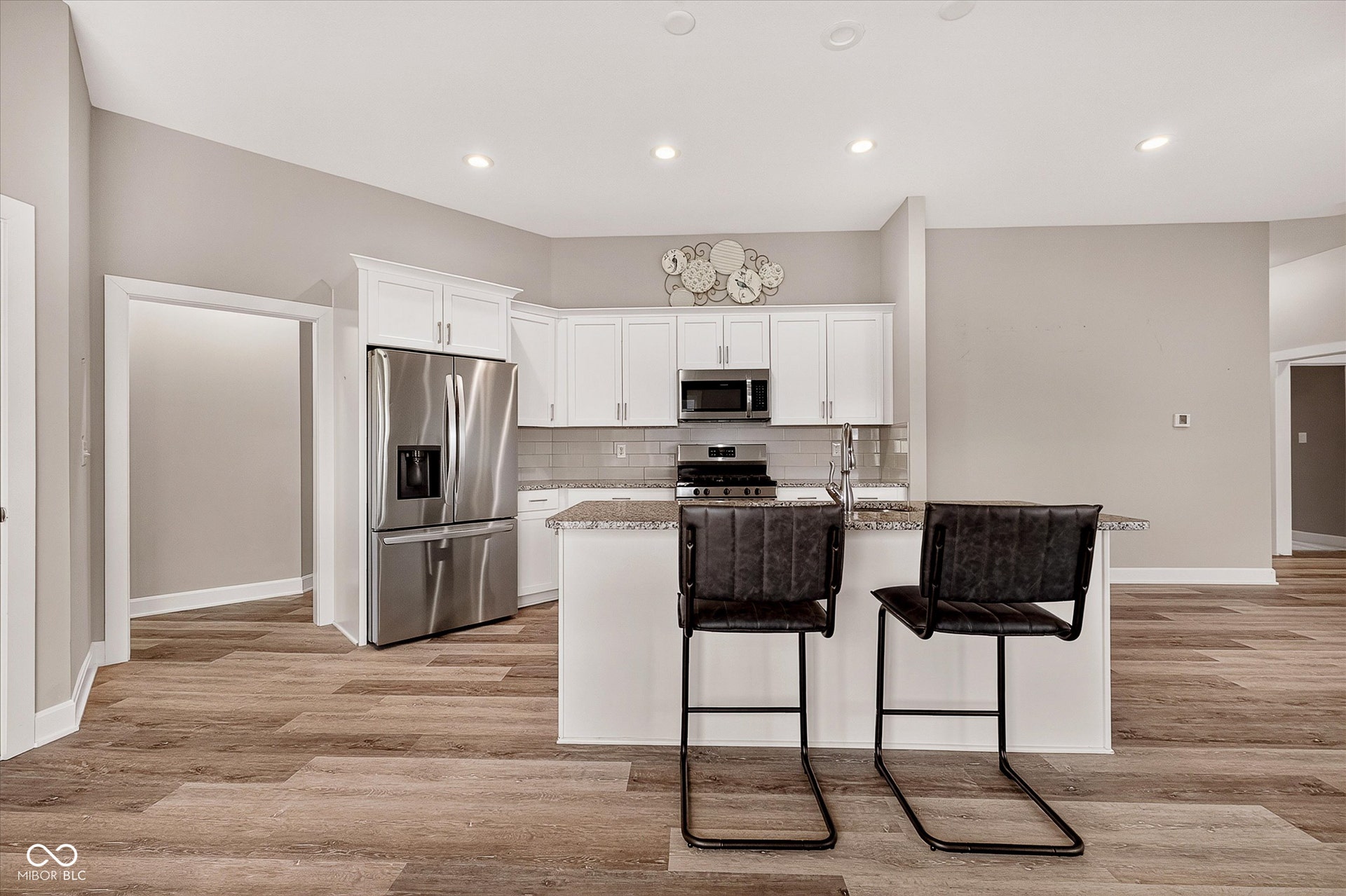 Kitchen featuring stainless steel appliances, white cabinetry, granite countertops, and wood-finish flooring