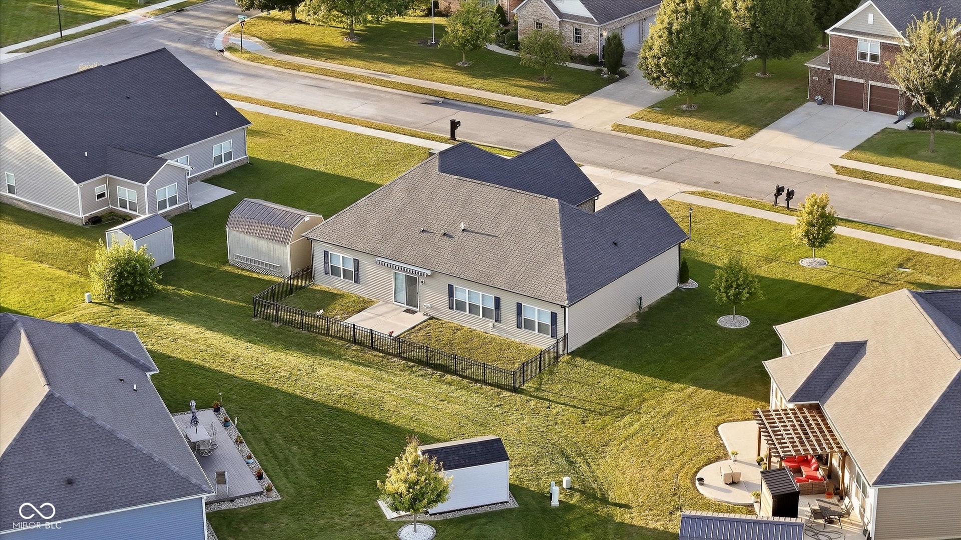 Expansive green space featuring a large residential structure with a light-colored exterior and dark roof