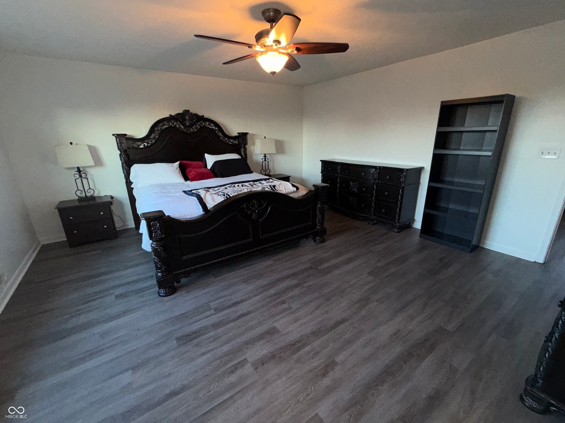 Wood-finish flooring with baseboards, white walls, and a ceiling fan with integrated lighting