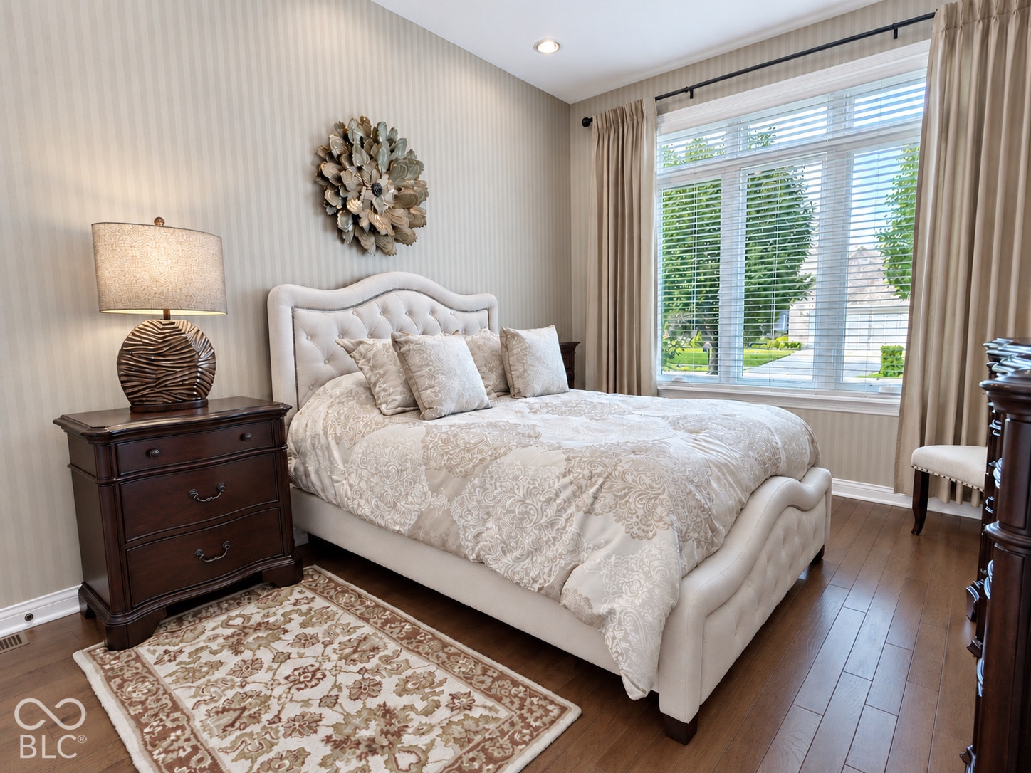 Hardwood flooring, large picture window with blinds and drapes, recessed lighting, and a neutral color palette