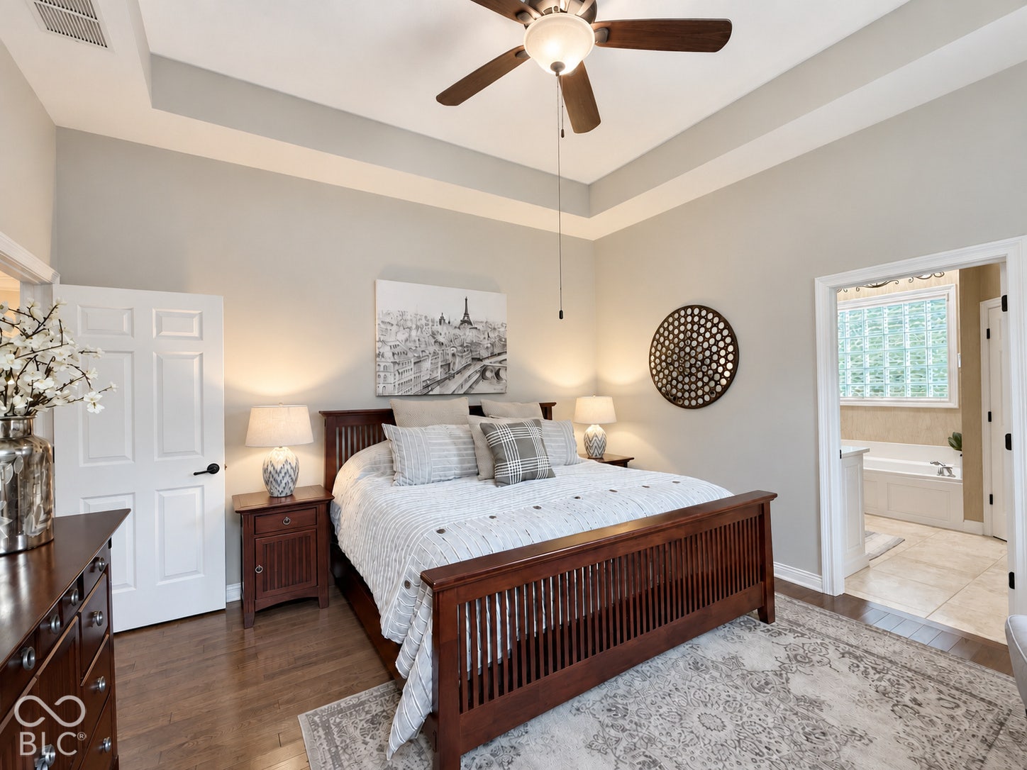 Tray ceiling with a ceiling fan, wood-finish flooring, and a six-panel door