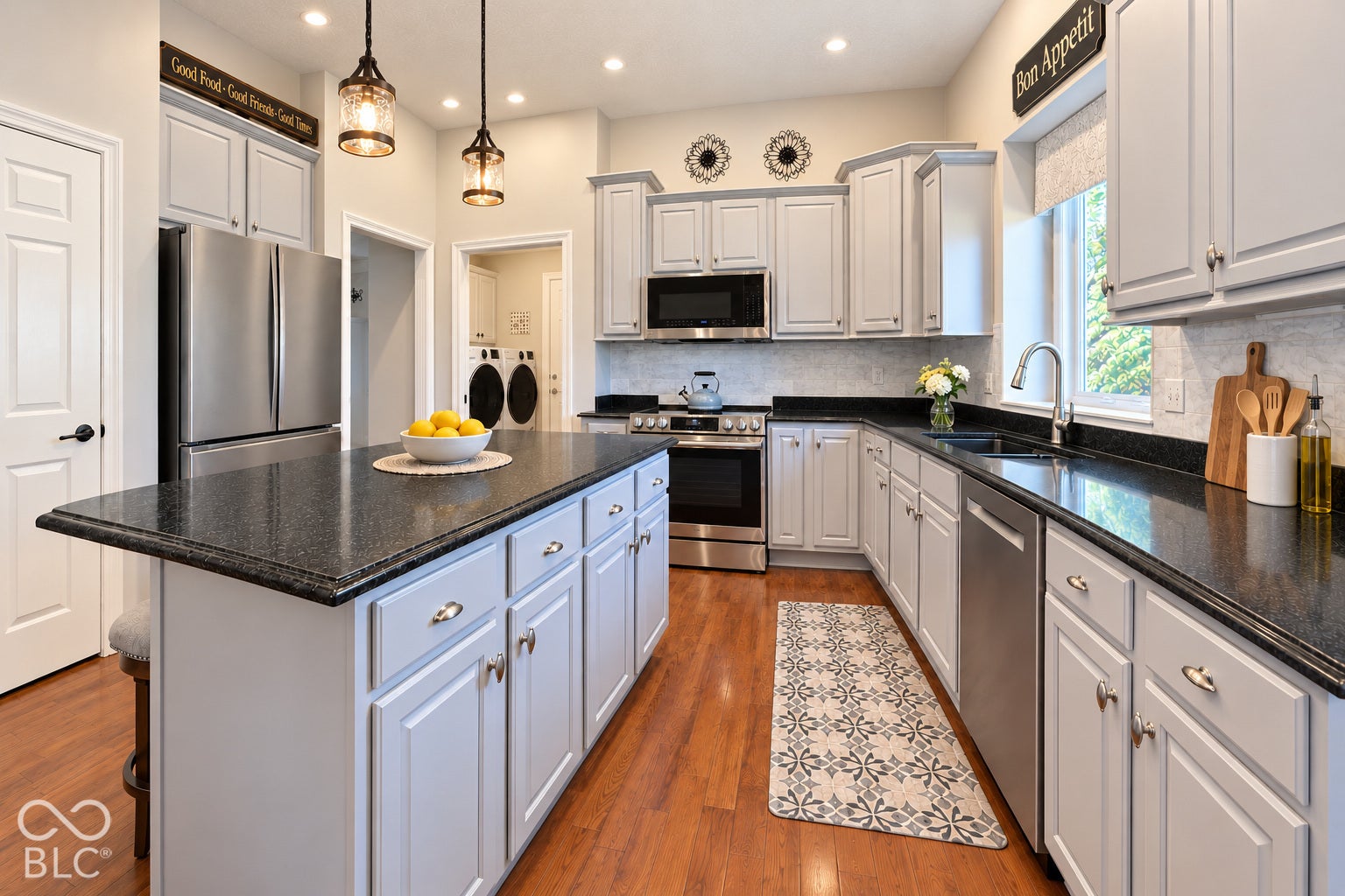 Virtually Altered - Kitchen featuring an expansive center island, stainless steel appliances, pantry, light-toned cabinetry, granite countertops, and engineered hardwood flooring