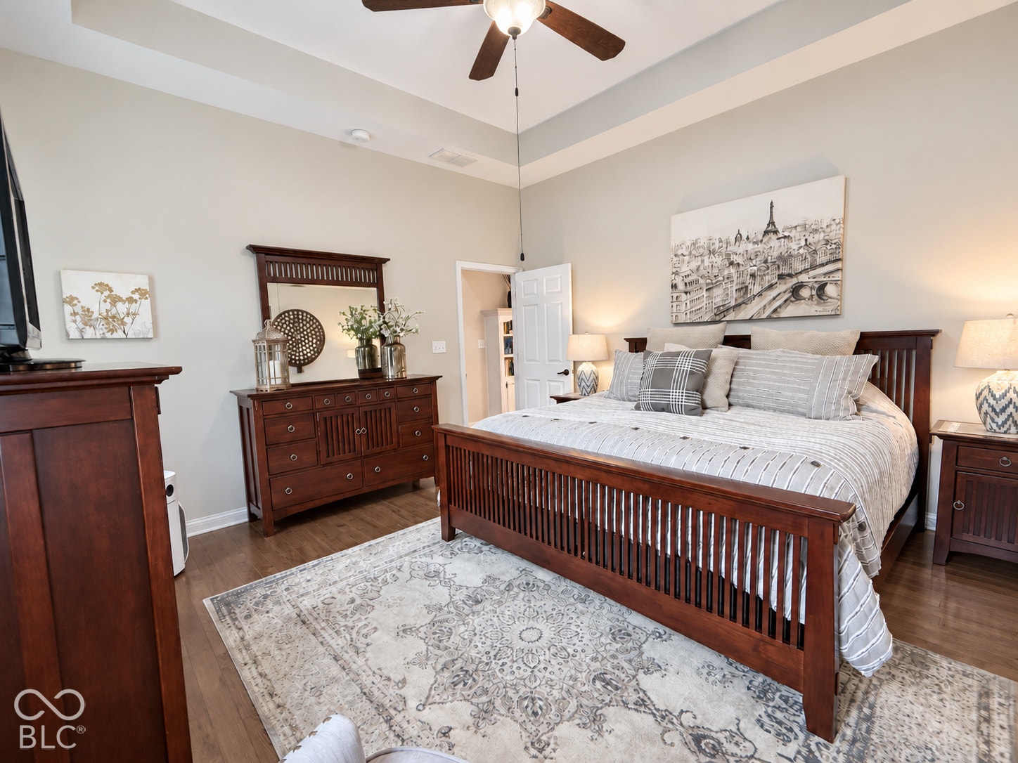 Tray ceiling with a ceiling fan, wood-finish flooring, and light wall paint