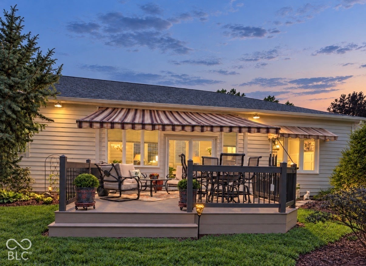 Rear elevated deck featuring a striped awning, shingle siding, and a dark railing system