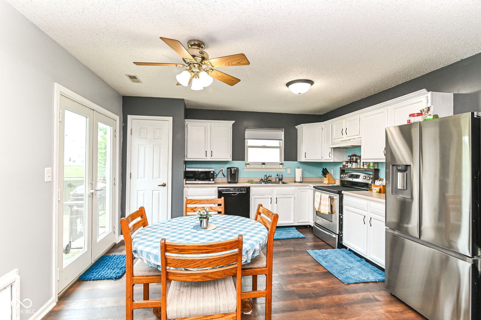 Kitchen featuring wood-finish flooring, white cabinetry, a stainless steel refrigerator, and French doors