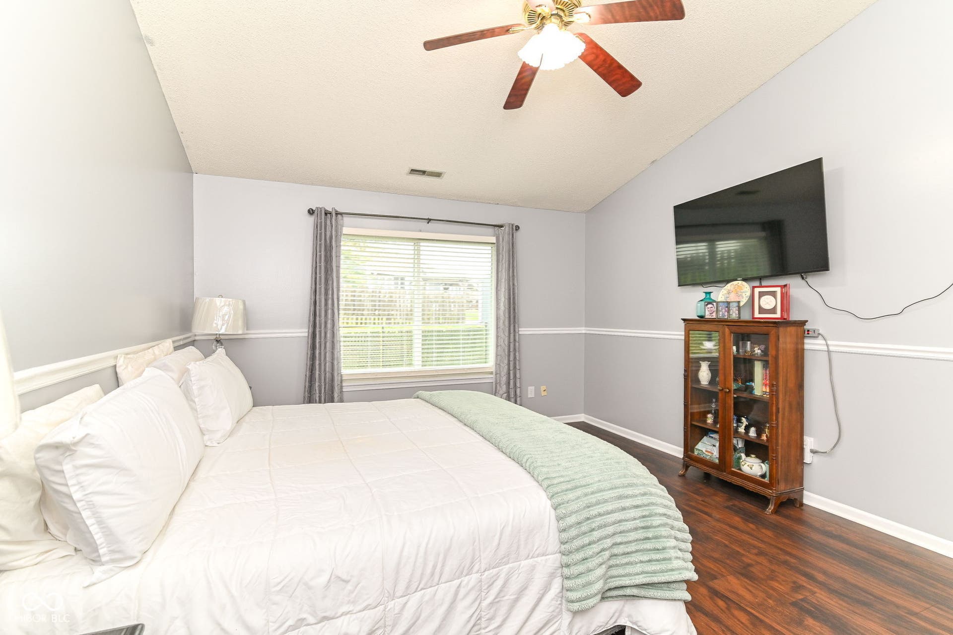 Vaulted ceiling with a ceiling fan, window with blinds, wood-finish flooring, and two-tone painted walls