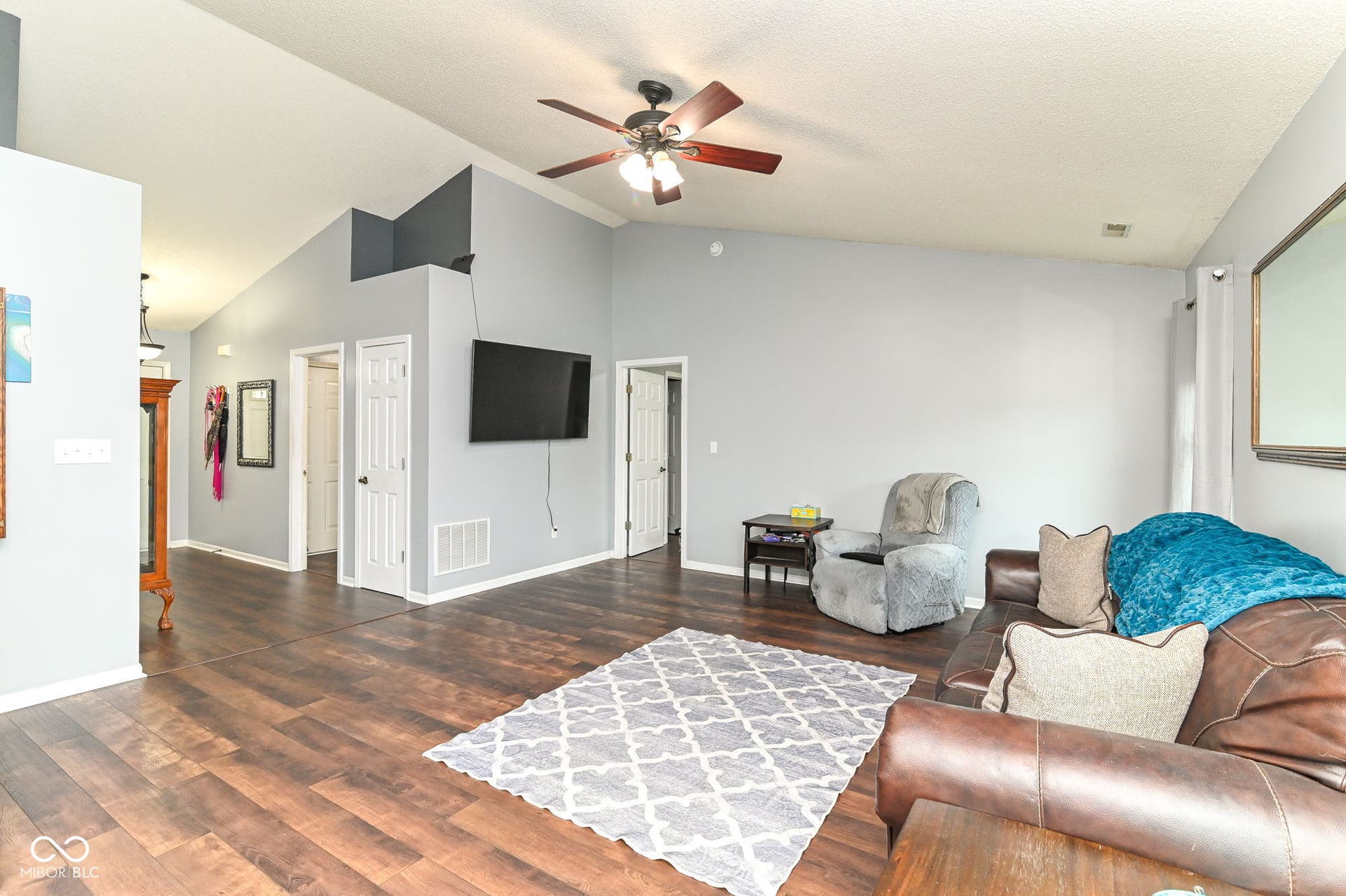 Vaulted ceilings, wood-finish flooring, ceiling fan with light fixture, light gray wall paint, white trim