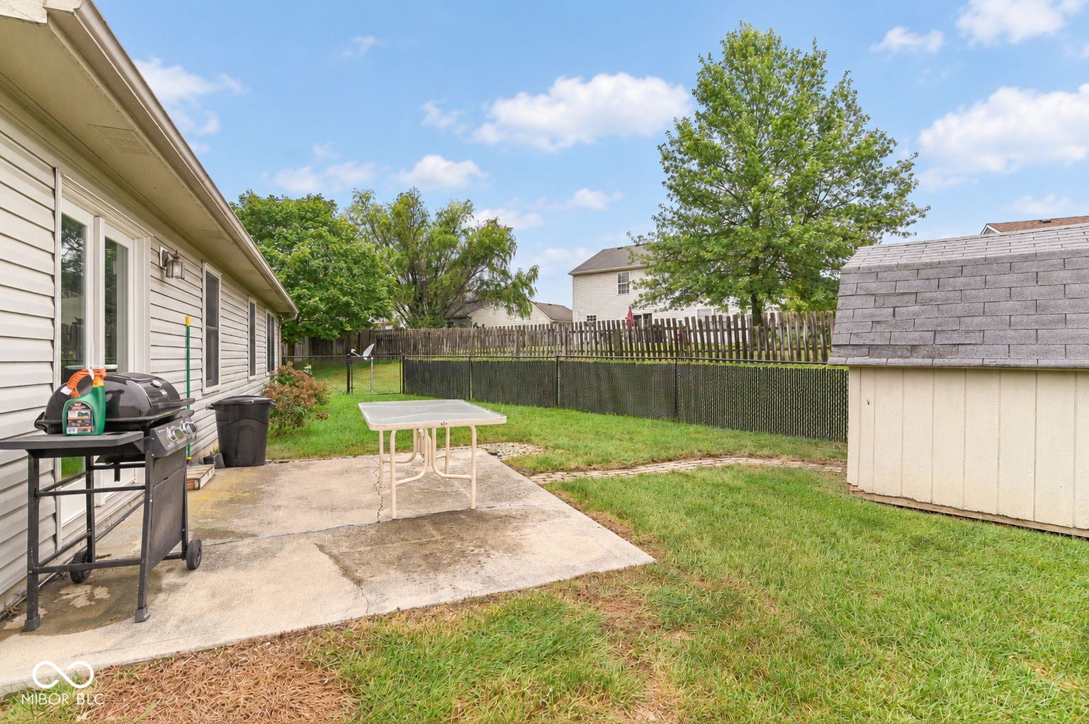 Concrete patio with a fully fenced yard and a detached storage shed