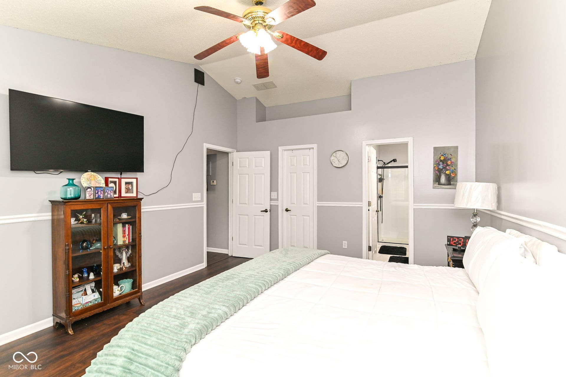 Vaulted ceiling with a ceiling fan, wood-finish flooring, and a walk-in shower with a glass enclosure