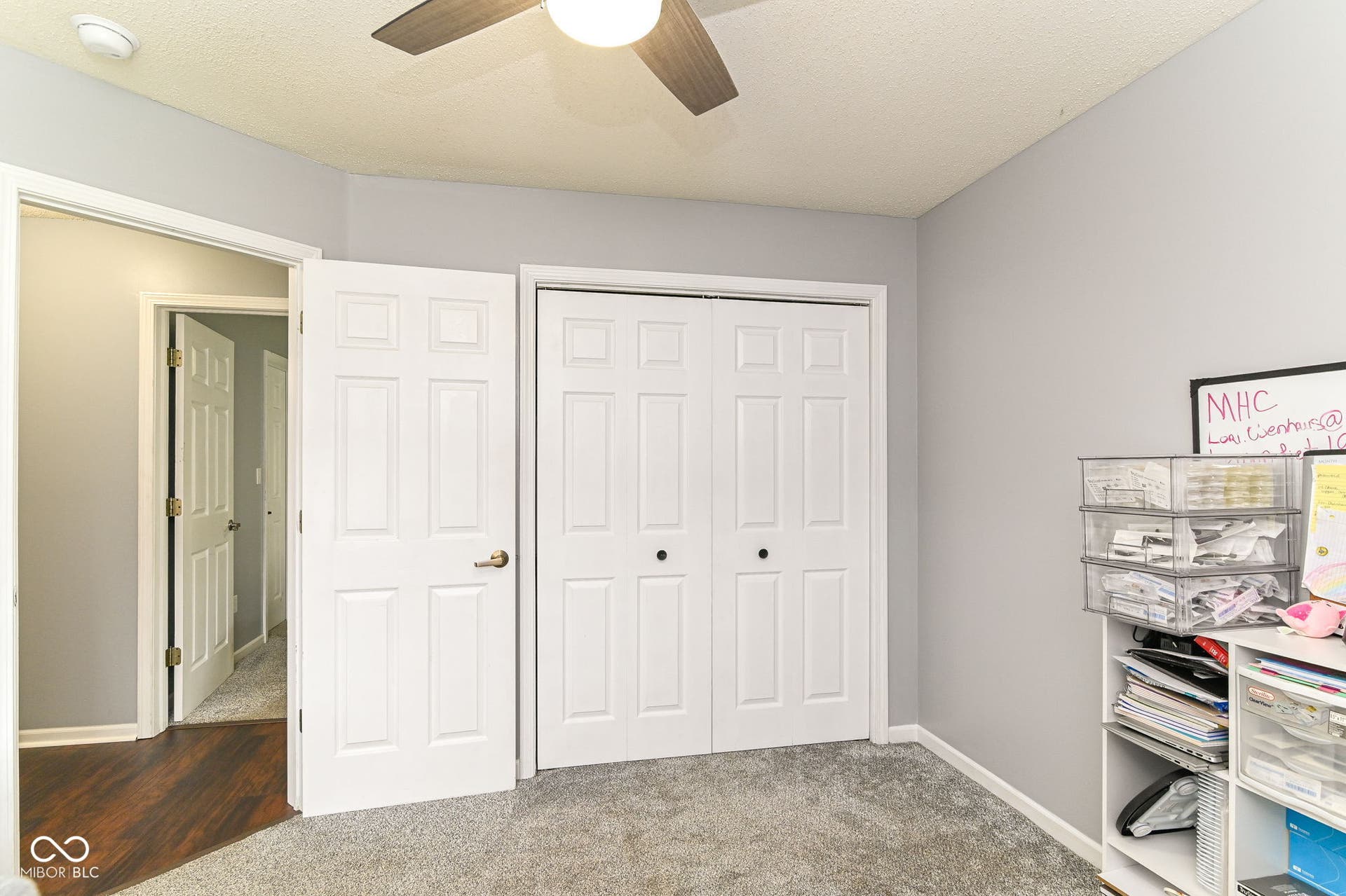 Neutral wall paint, carpeted flooring, paneled interior doors, and a ceiling fan with integrated lighting