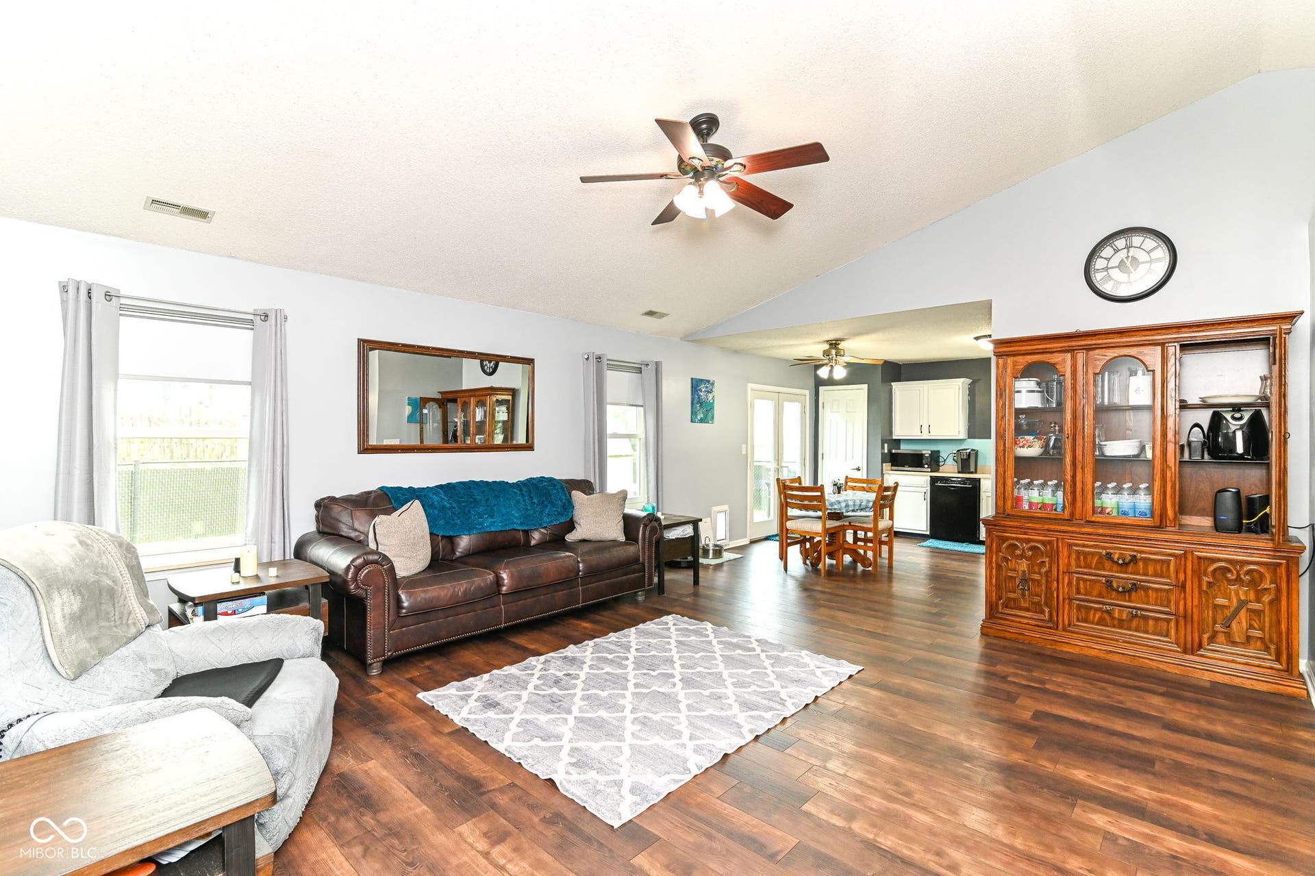 Vaulted ceiling with a ceiling fan, wood-finish flooring, multiple windows, and a classic wood hutch