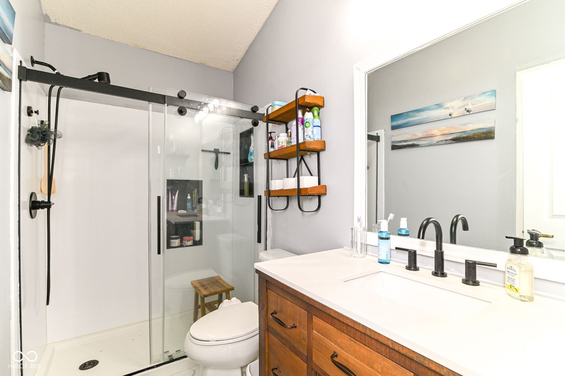 Glass-enclosed shower with matte black hardware and built-in shelving