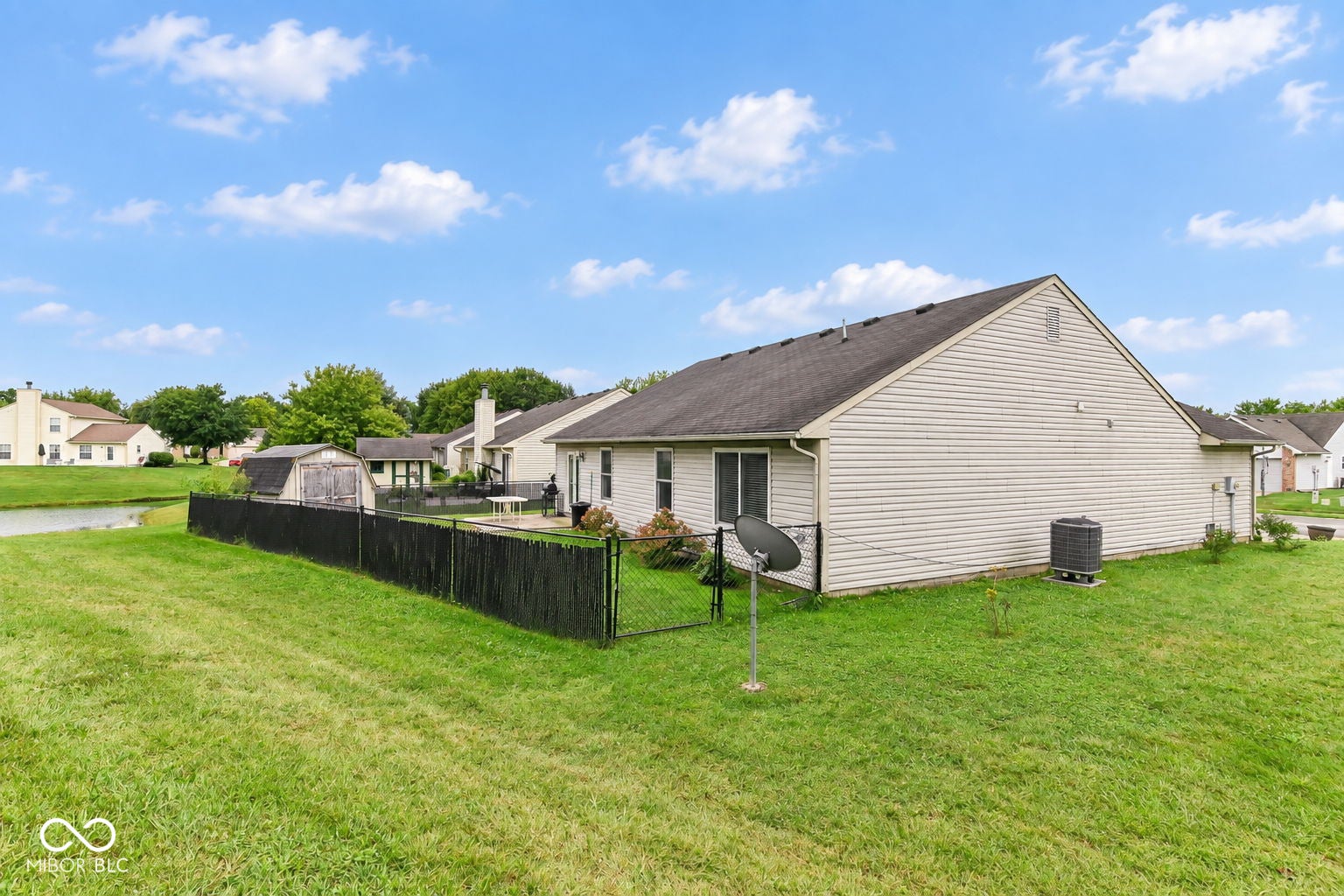 Expansive grassy yard with a black privacy fence