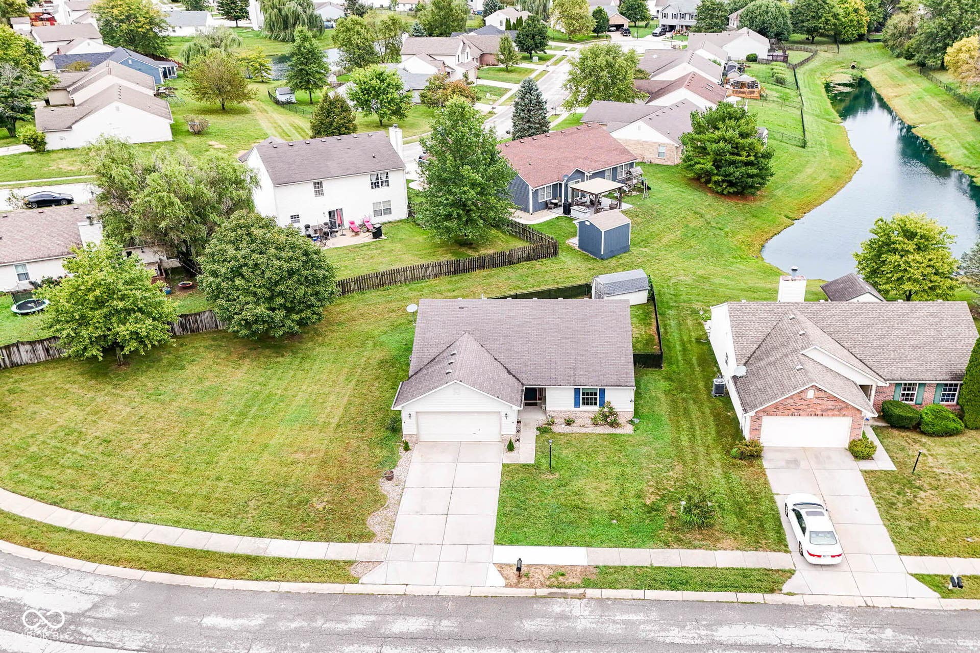 Residential property featuring a concrete driveway, attached garage, and surrounding green spaces