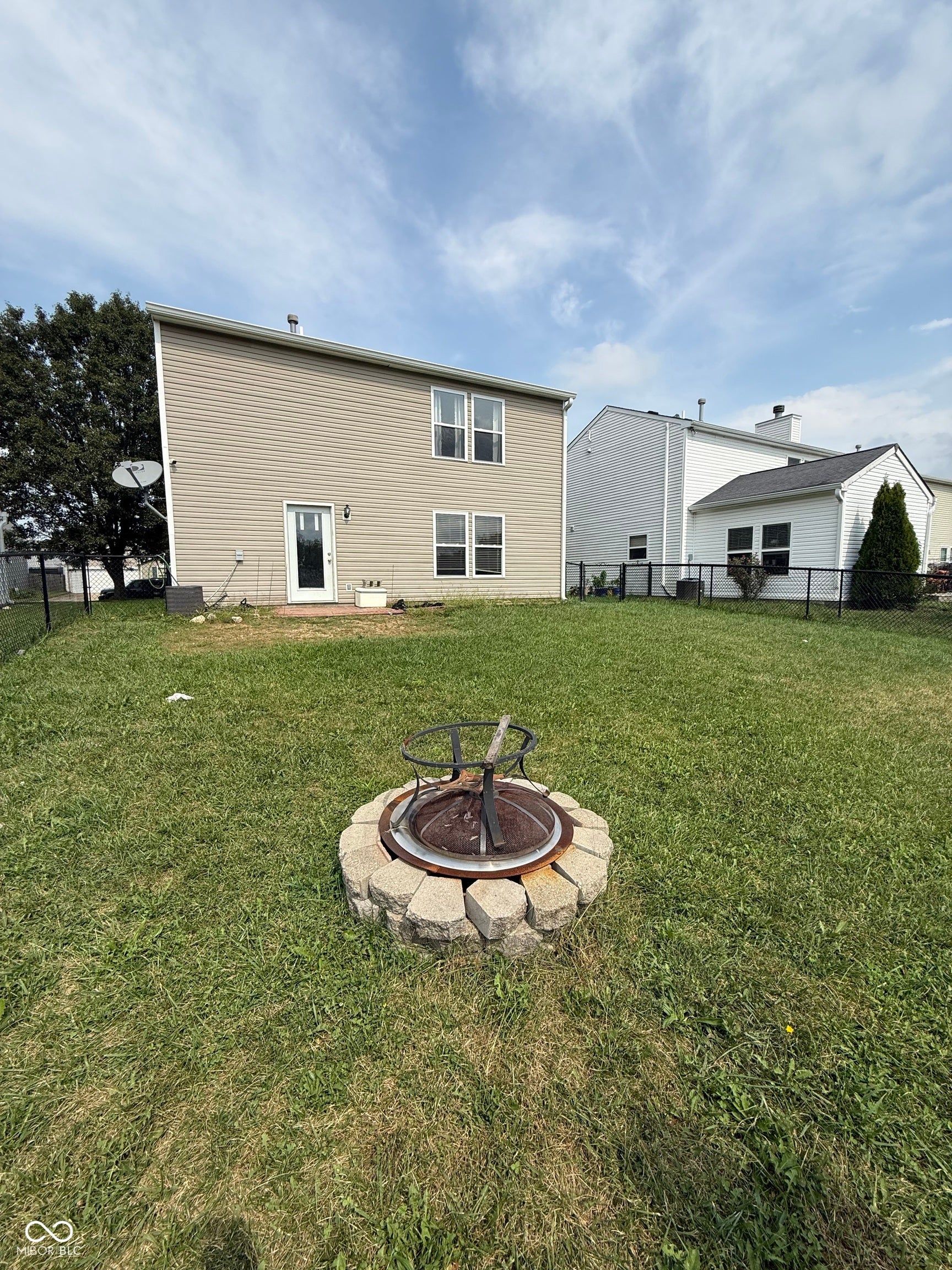 6235 E Mariah Hill Lane, Camby, IN 46113 Backyard featuring a stone fire pit, fenced perimeter, and rear entry door