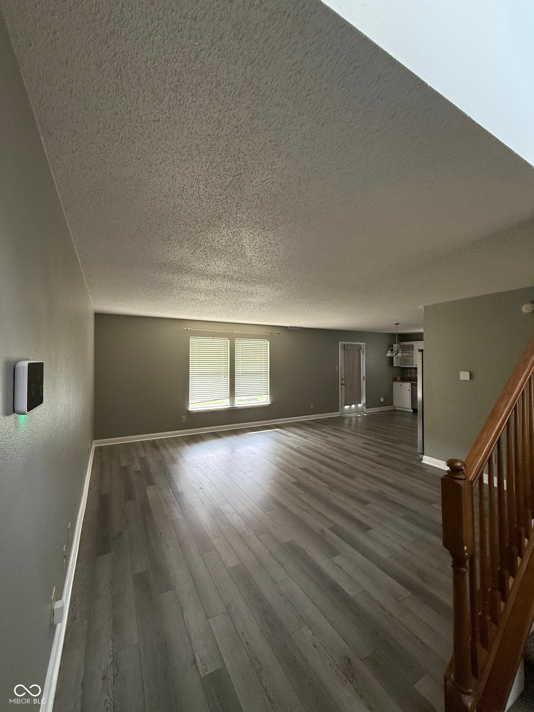 6235 E Mariah Hill Lane, Camby, IN 46113 Spacious open-concept living area showcasing wood-finish plank flooring, vaulted ceiling with recessed lighting, and abundant natural light from dual windows