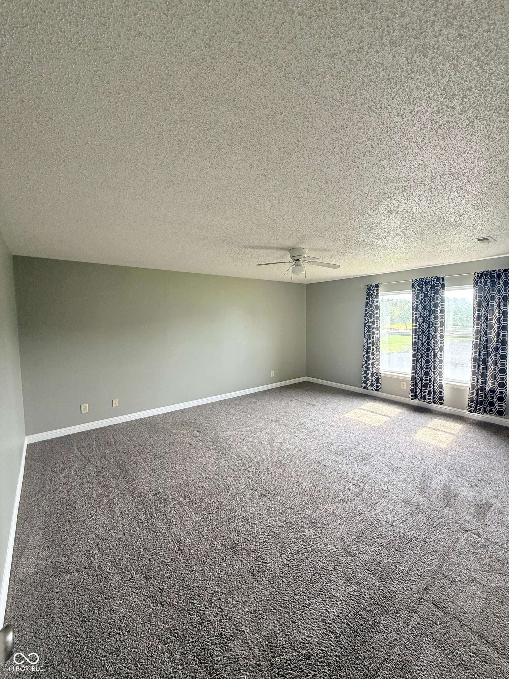 6235 E Mariah Hill Lane, Camby, IN 46113 Spacious interior with gray carpeting, light gray walls, multiple windows, and a ceiling fan
