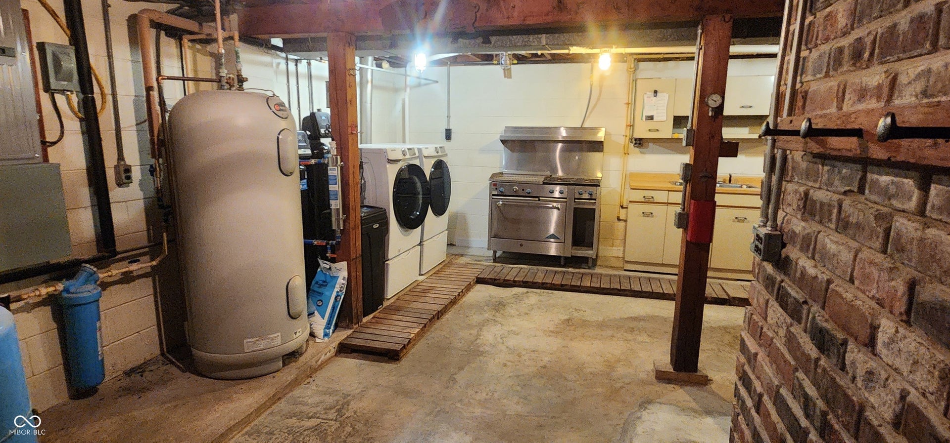 Utility space with exposed brick, concrete flooring, and an industrial-style range