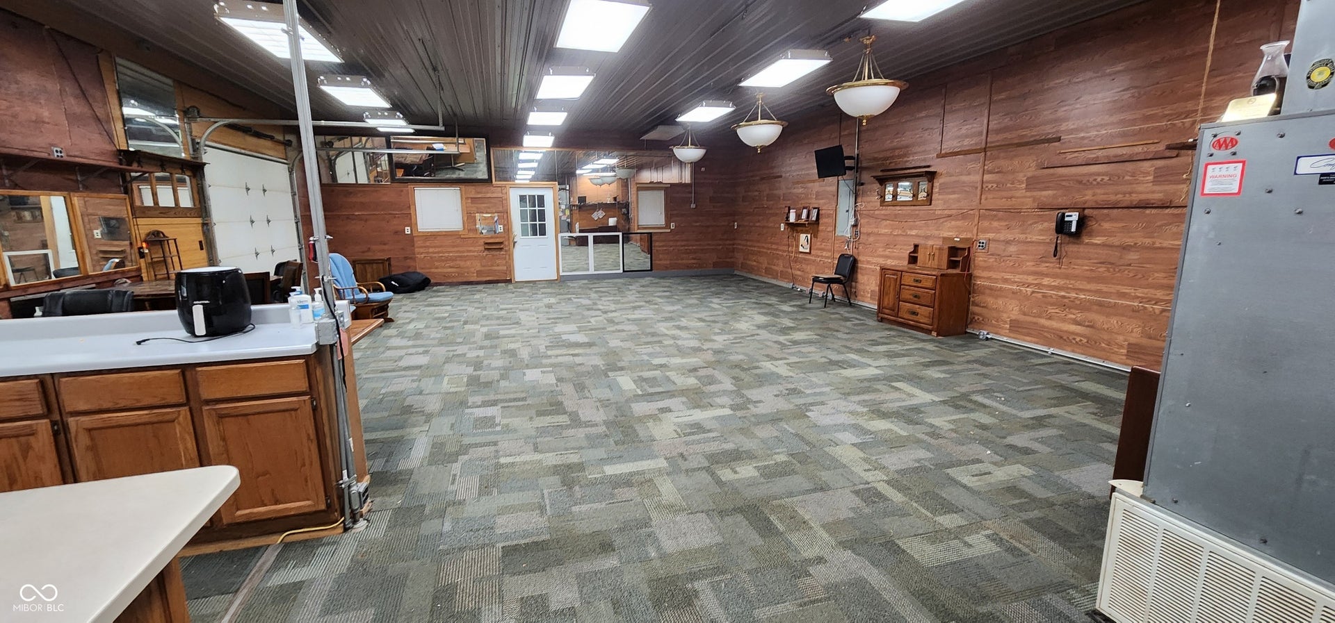 Expansive open room featuring patterned carpet flooring and wood-paneled walls
