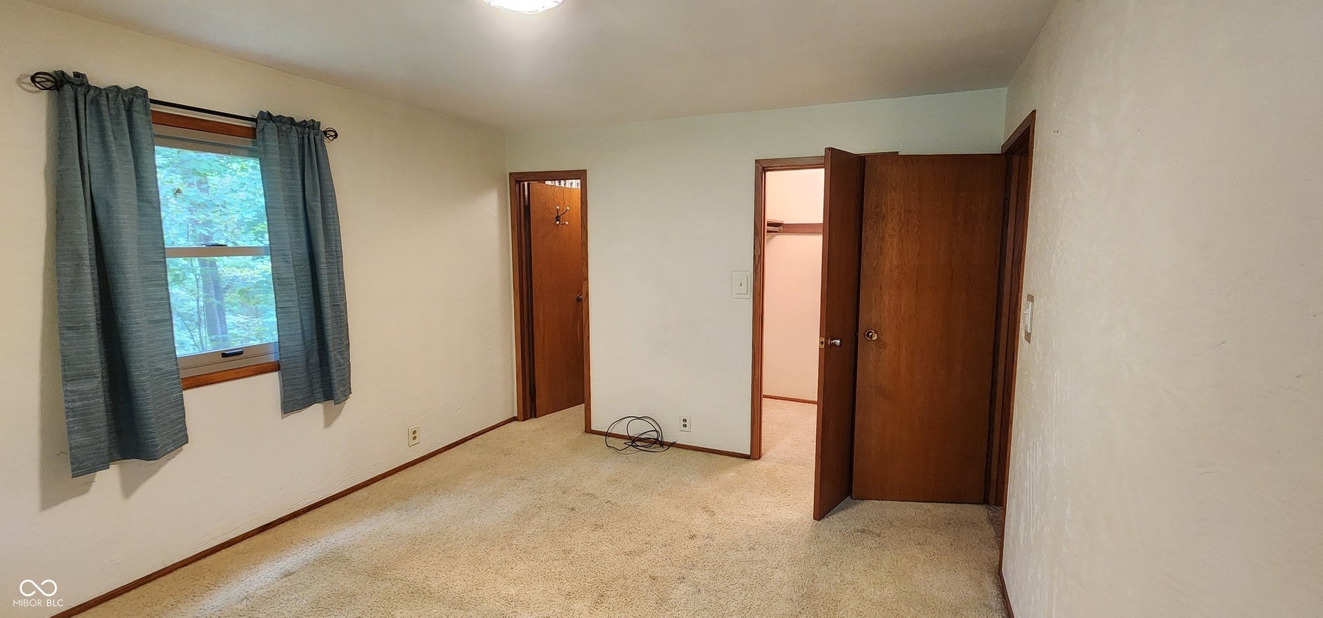 Carpeted flooring, white painted walls, and wood-finish trim and doors