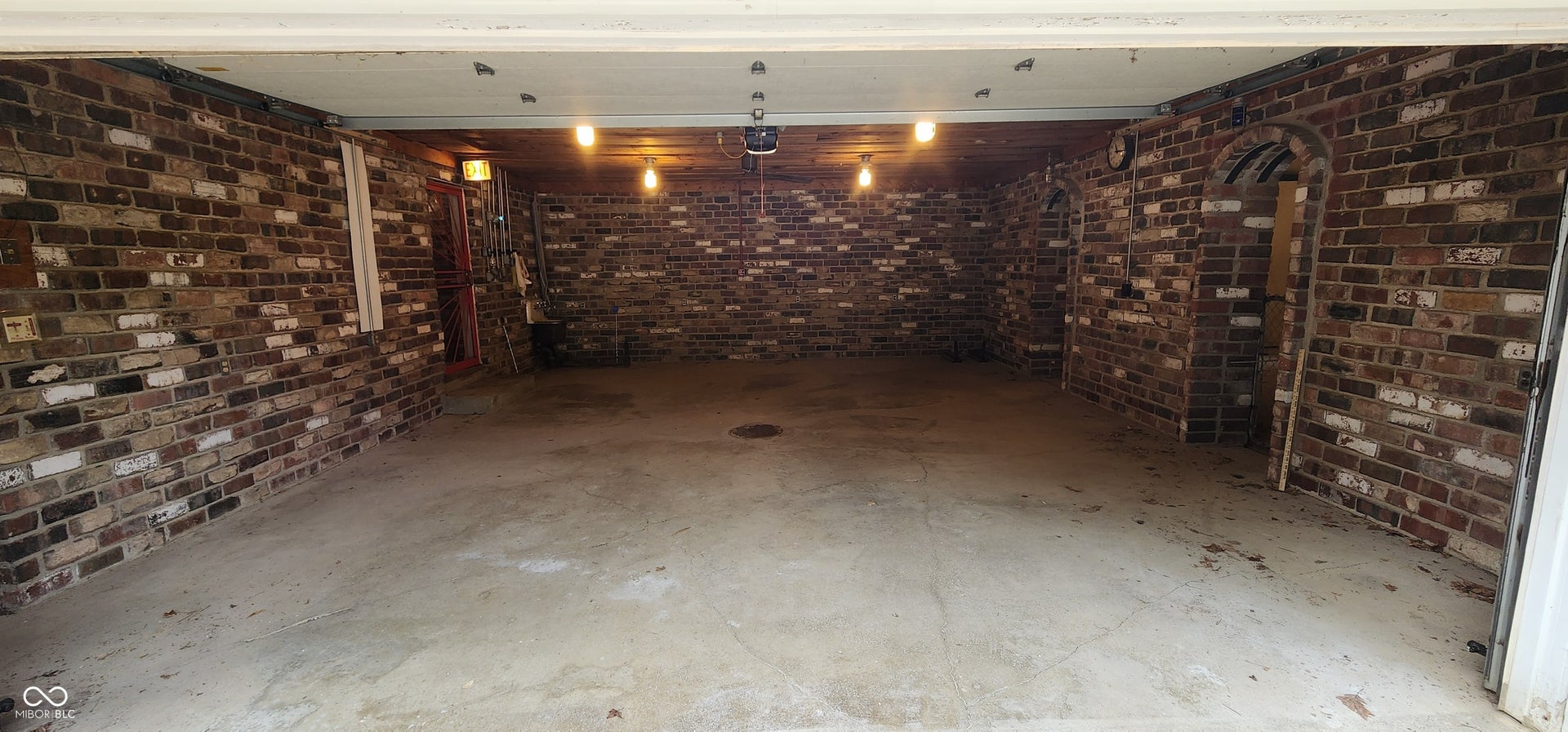 Concrete flooring with brick walls, exposed ceiling joists, and integrated lighting