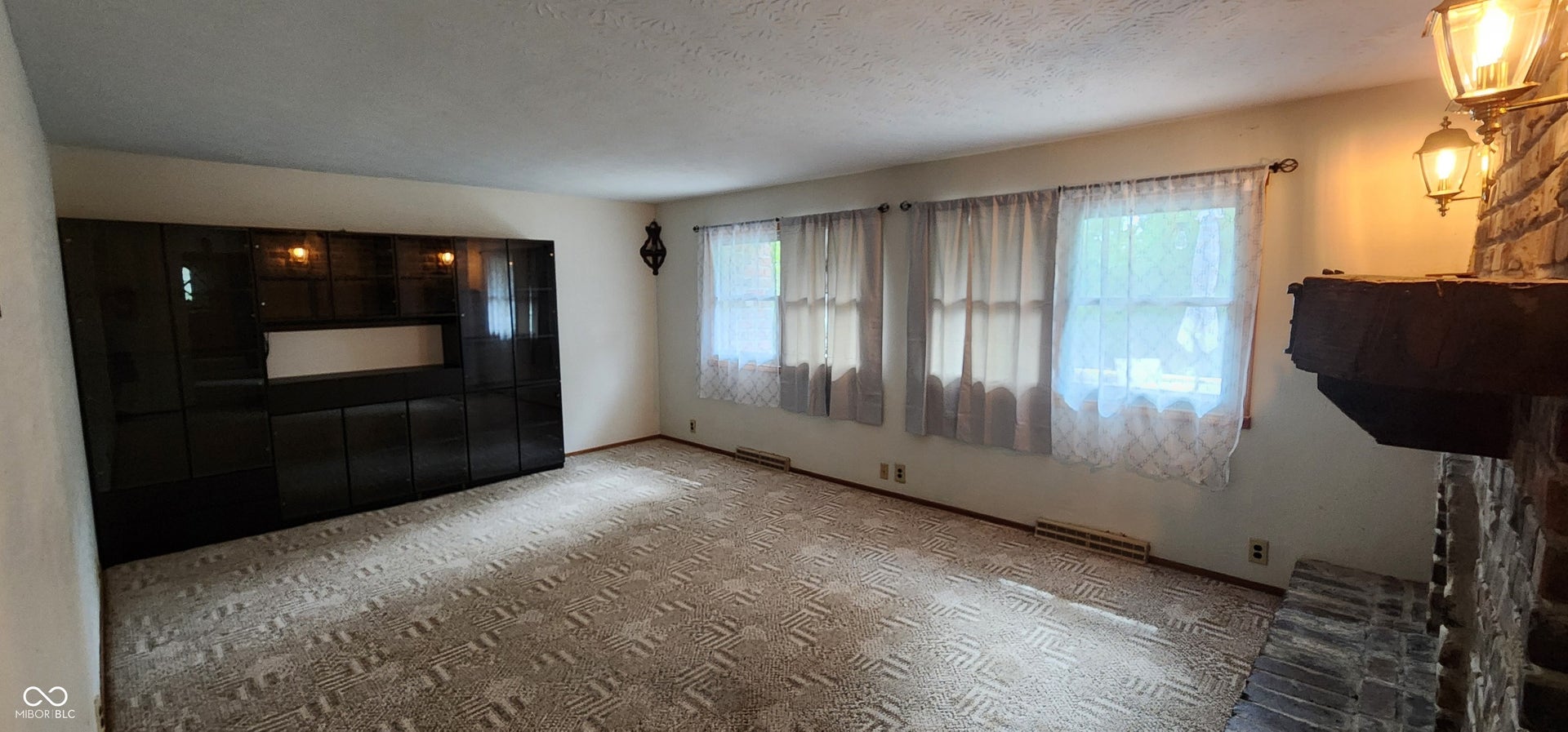 Built-in cabinetry with integrated lighting, brick fireplace, wood mantel, and multiple windows