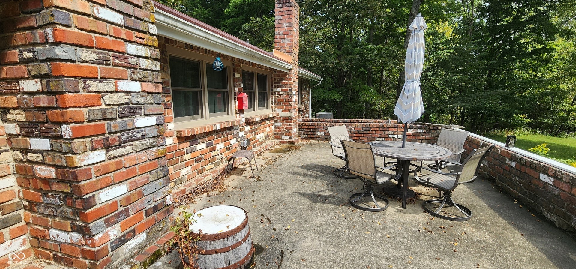 Expansive patio area featuring a brick exterior, multiple windows, and a surrounding brick wall