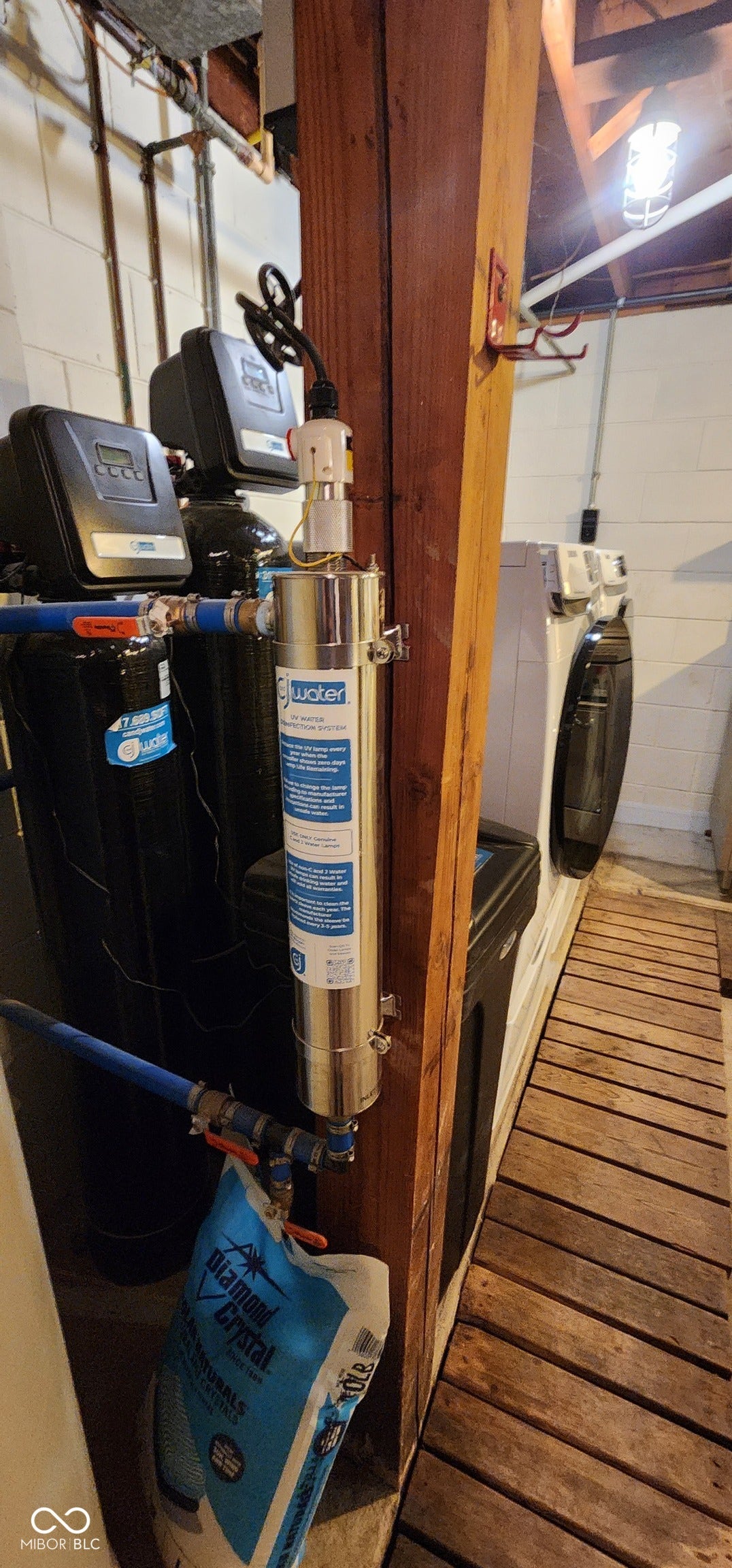 Water filtration system with associated plumbing and a nearby wood slat floor section