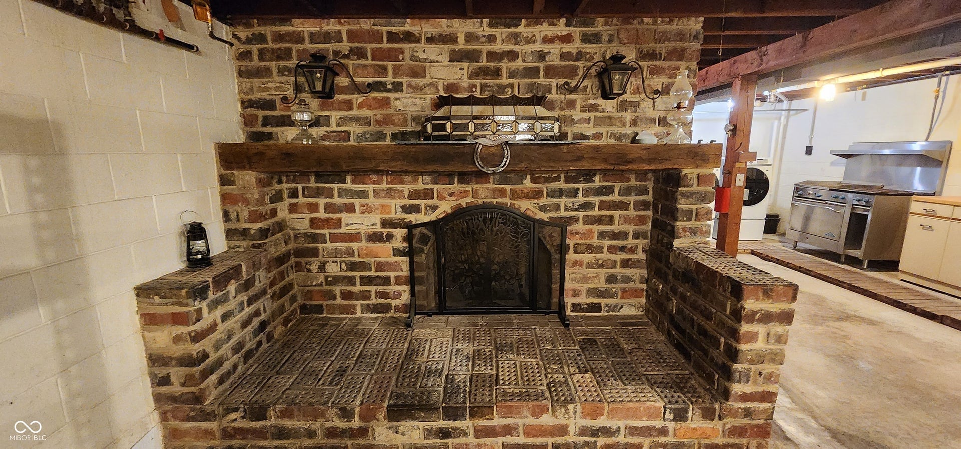 Basement exposed brick fireplace with a wood mantle and wrought iron details