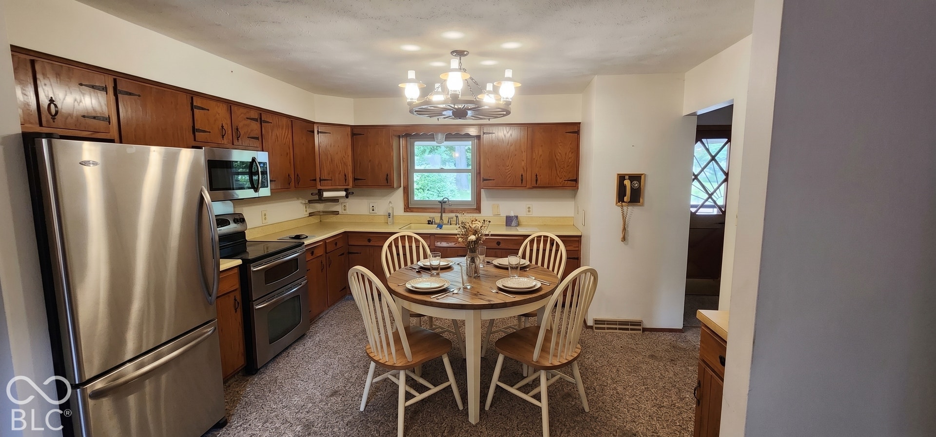 Virtually Altered - Kitchen featuring wood cabinetry, stainless steel appliances, and a built-in dining area