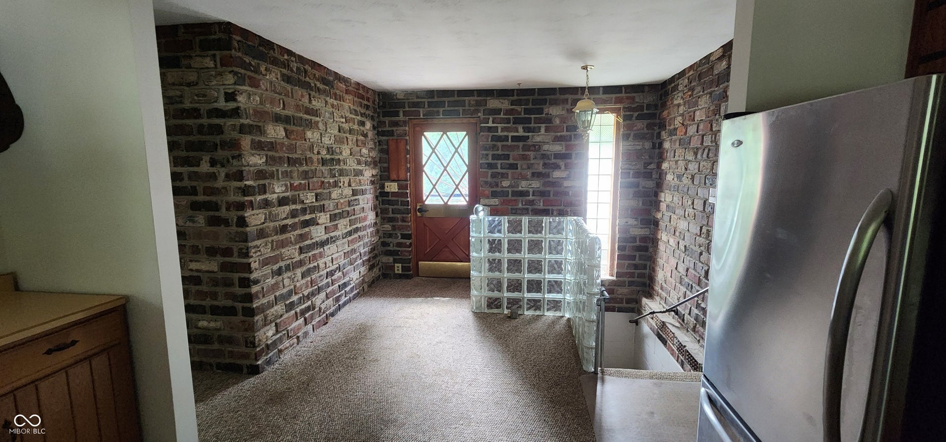 Brick accent walls, glass block partition, wood-paneled door with diamond-pane window, and a built-in wood-finish cabinet