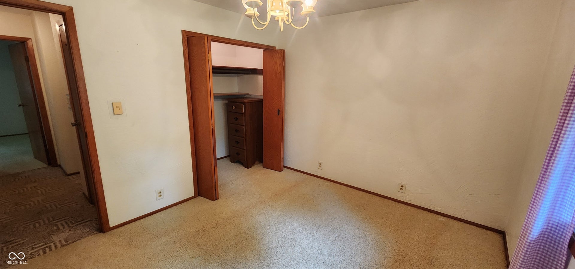 Carpeted room featuring a built-in closet with bi-fold doors and a ceiling-mounted chandelier