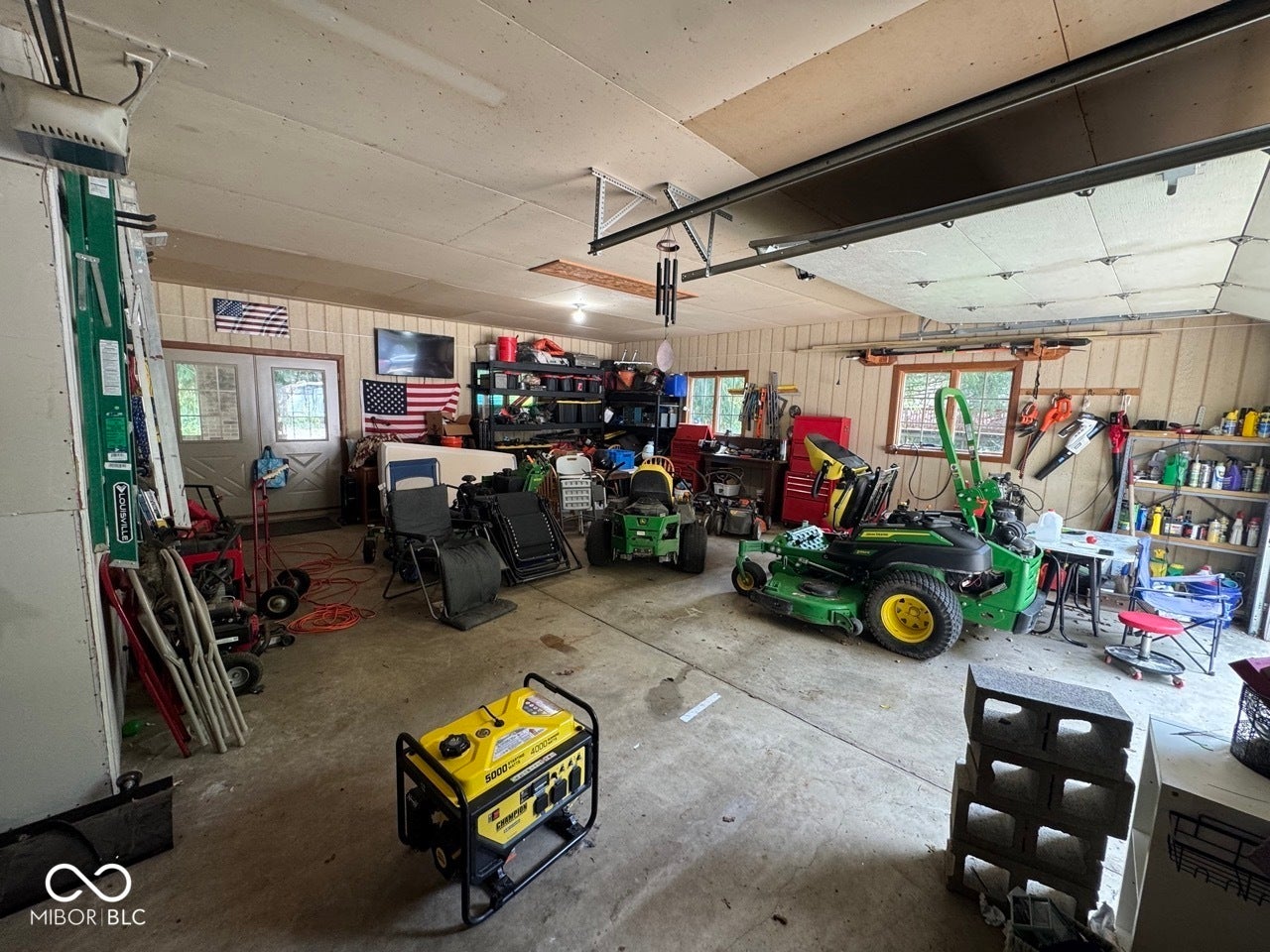 Spacious garage with overhead lighting, concrete flooring, and multiple windows
