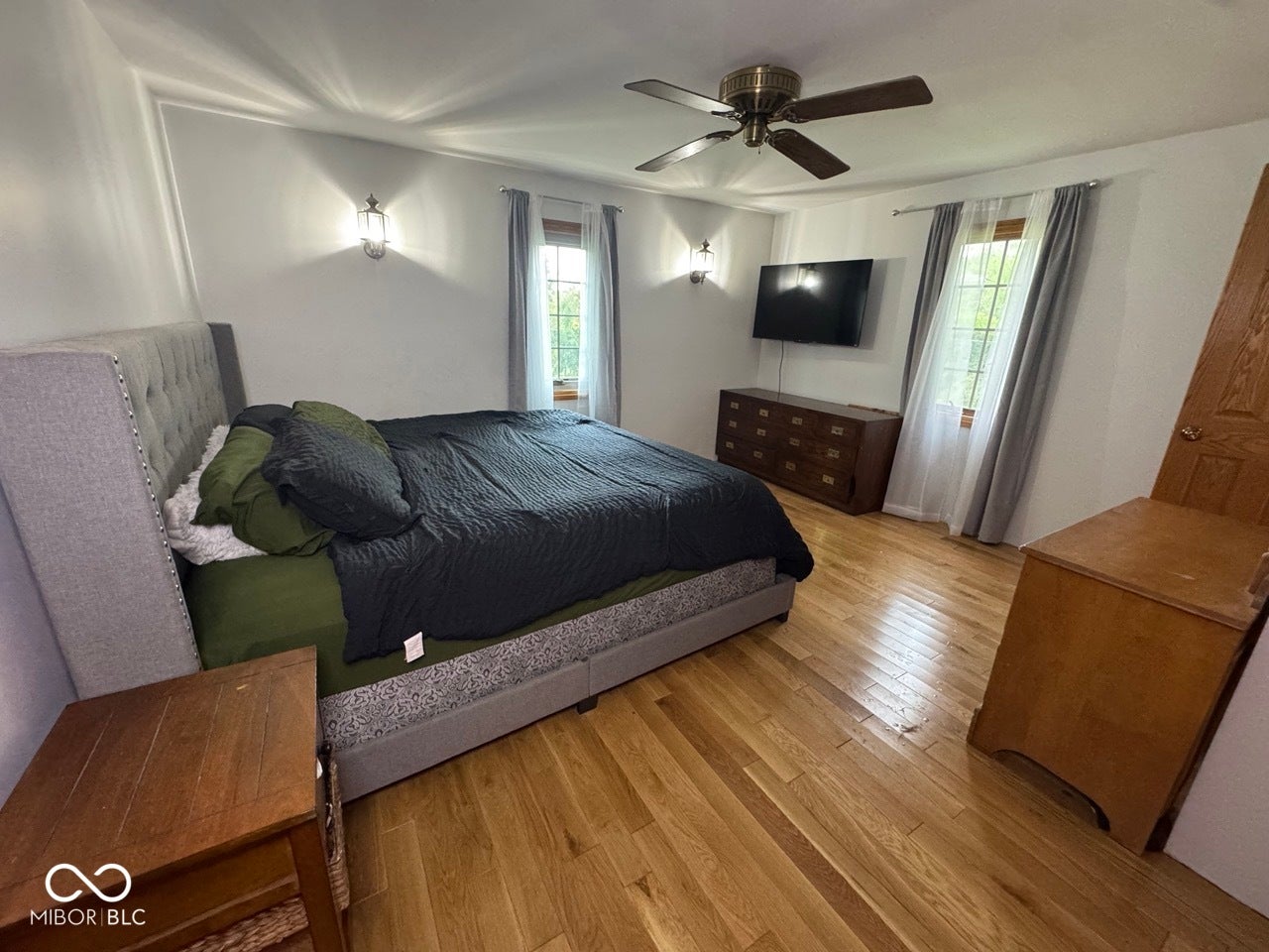 Hardwood flooring, ceiling fan, and wall-mounted sconces