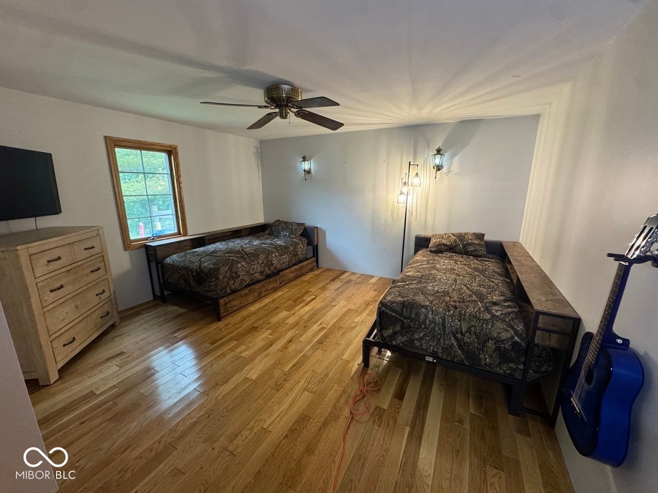 Hardwood flooring, ceiling fan, and window with wood-frame trim