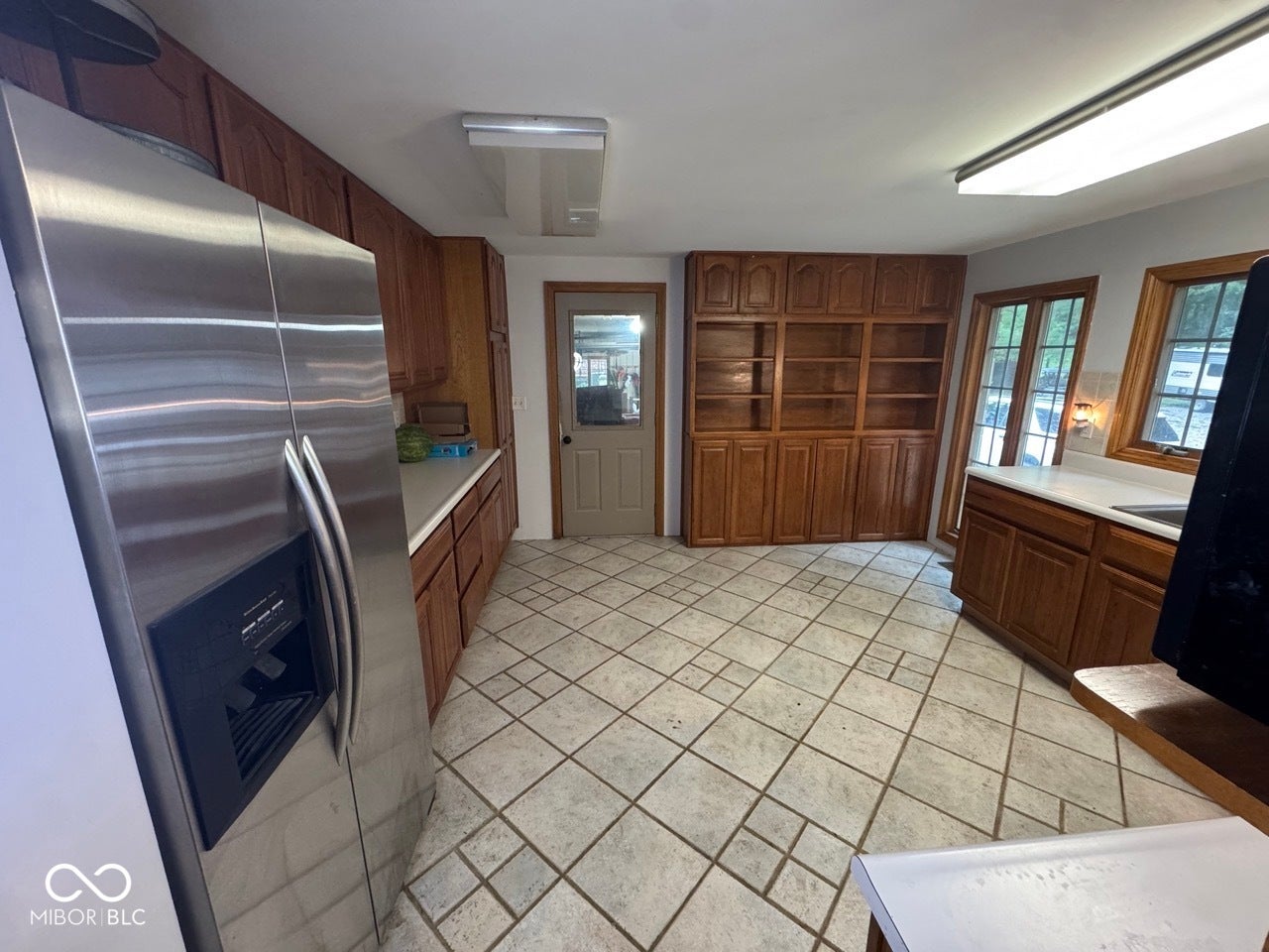 Kitchen featuring extensive wood-finish cabinetry, light-toned countertops, and a stainless steel refrigerator