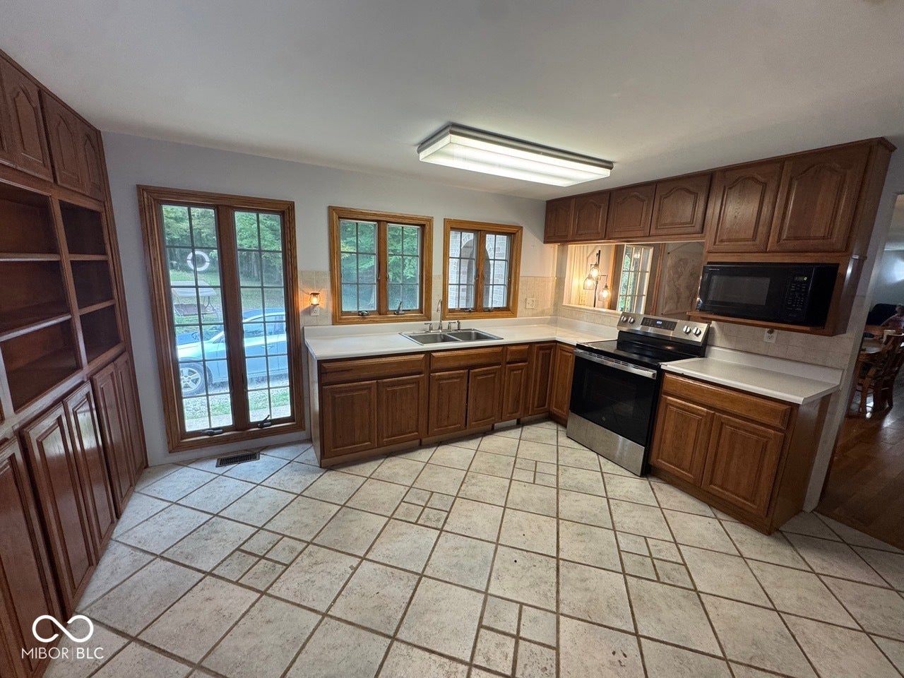 Kitchen featuring wood cabinetry, light countertops, tile flooring, and integrated stainless steel appliances