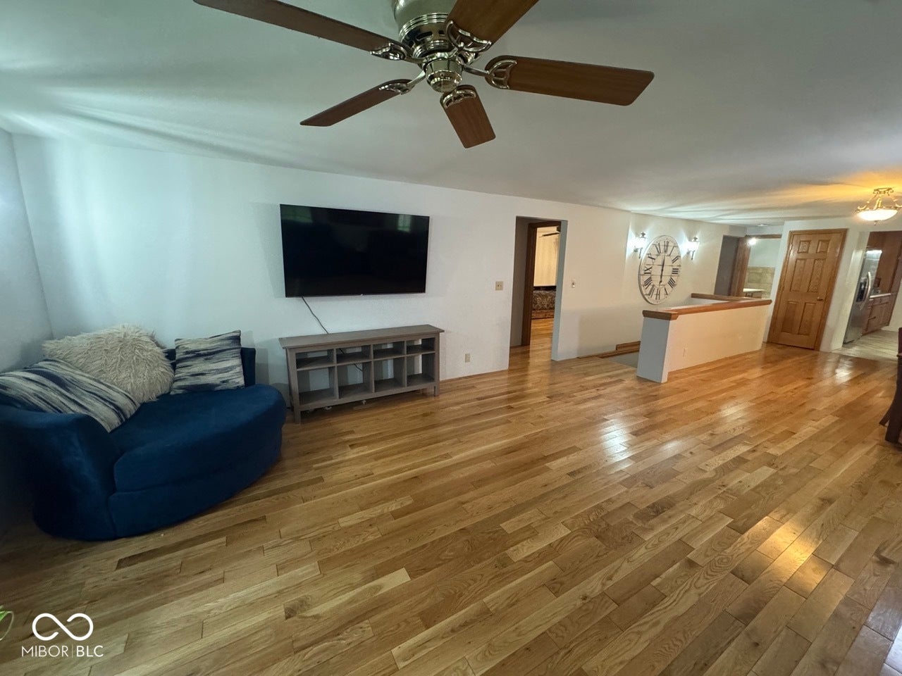 Hardwood flooring throughout, ceiling fan with wood-finish blades, and recessed wall lighting