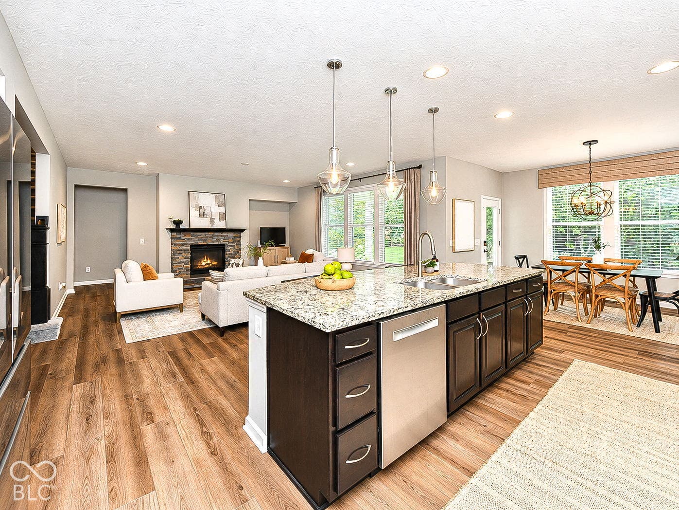 Spacious open-concept layout featuring wood-finish flooring, a kitchen island with stone countertop, and pendant lighting