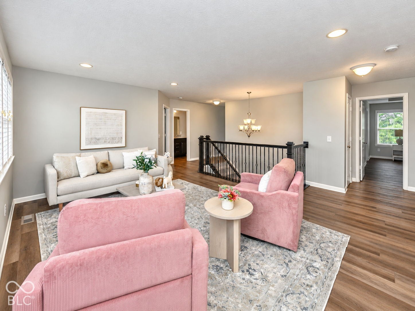 Hardwood-style flooring throughout, recessed lighting, and a wrought iron staircase with dark wood newel posts