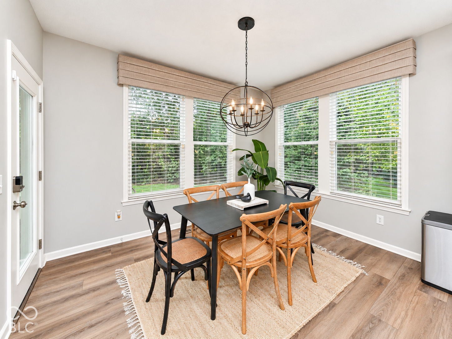 Corner window placement, wood-finish flooring, white trim, and a spherical chandelier