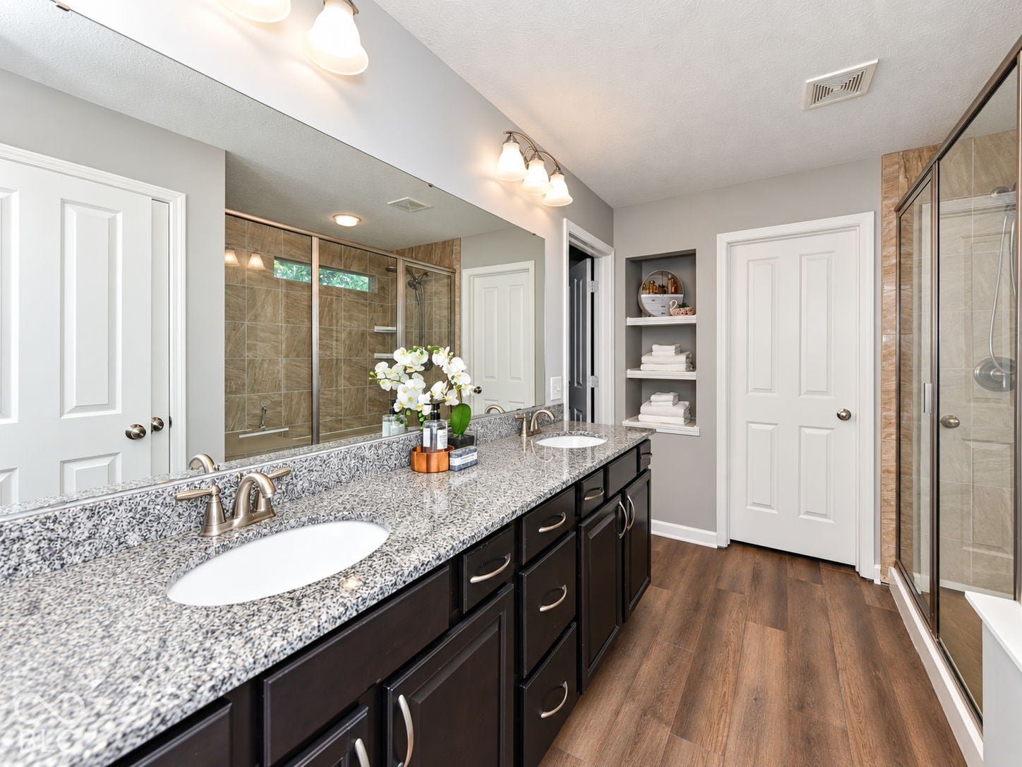Dual vanity with stone-finish countertop, dark wood-finish cabinetry, and brushed nickel fixtures