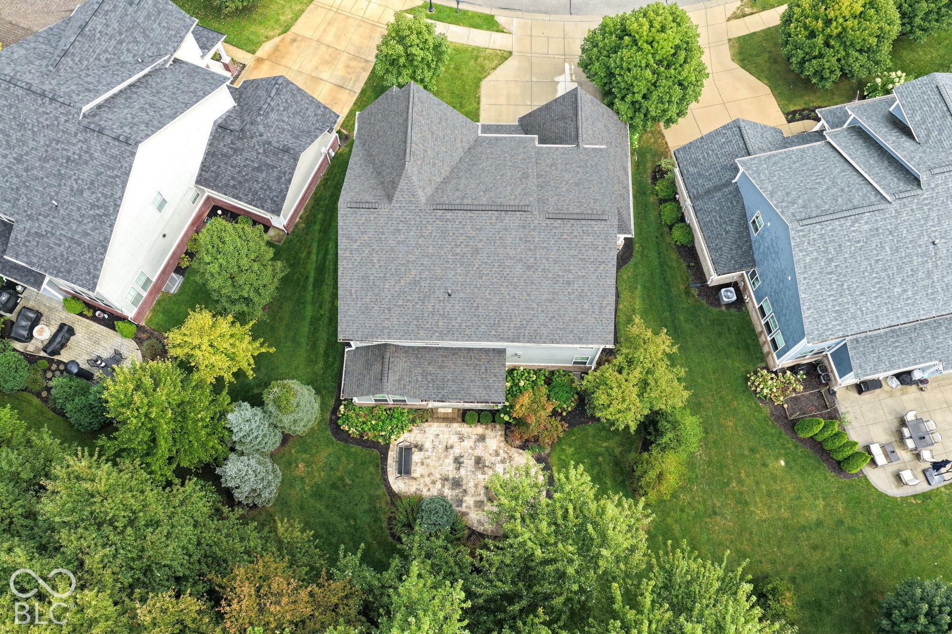 Manicured landscaping, paved patio, and mature trees