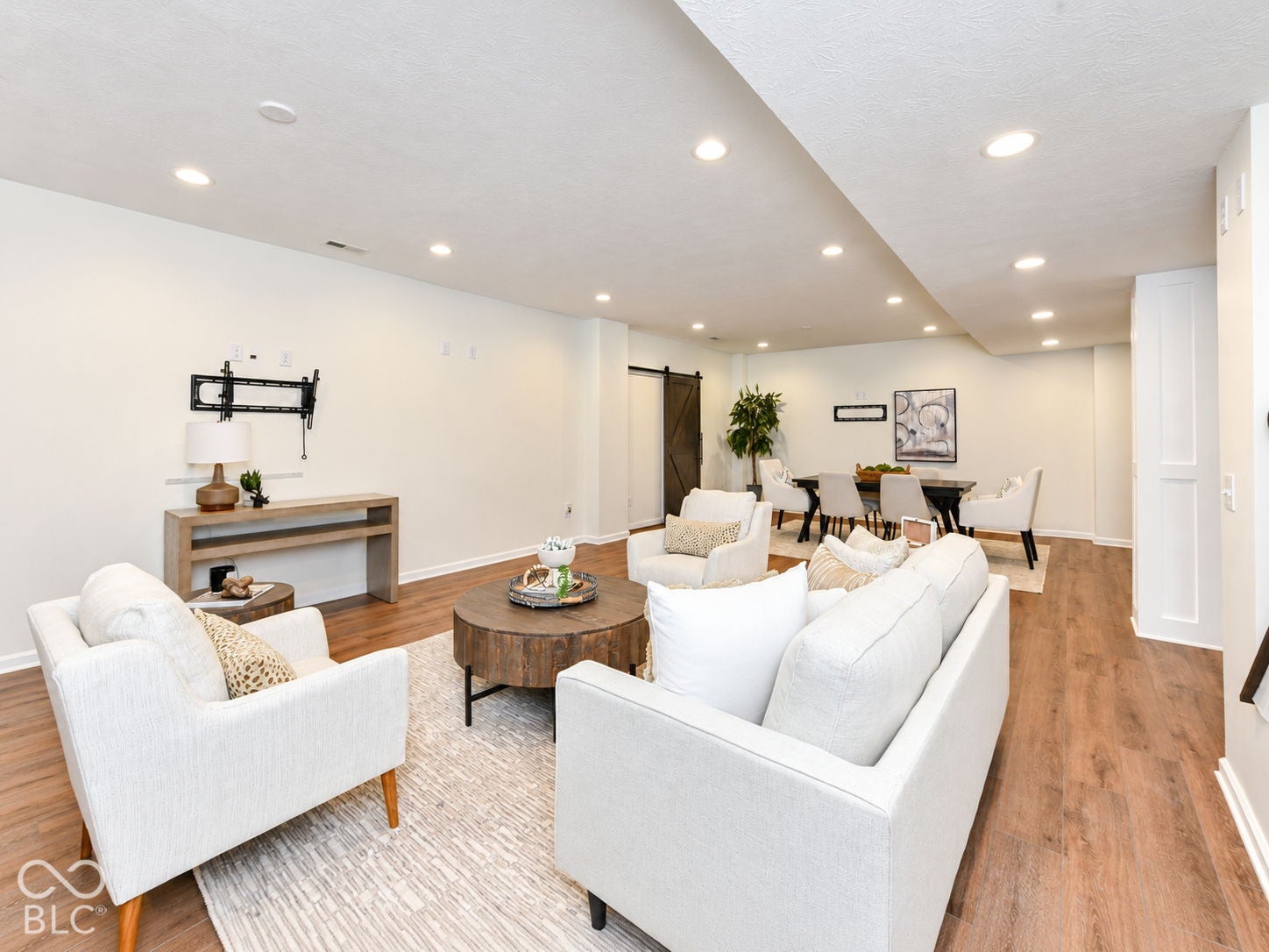Recessed lighting throughout, wood-finish flooring, and a barn door entry to a separate area