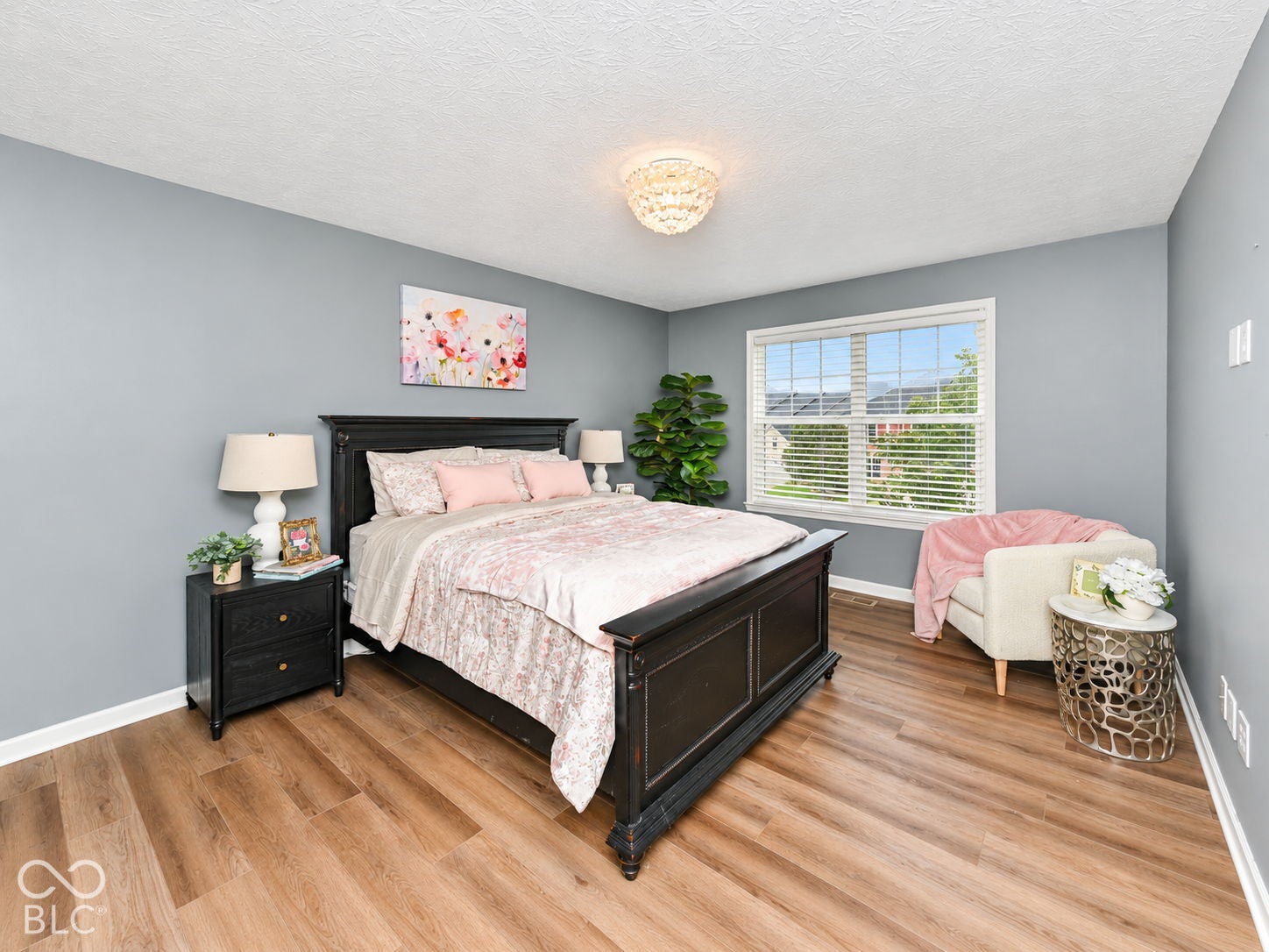 Wood-finish flooring, a large window with blinds, and a built-in overhead light fixture