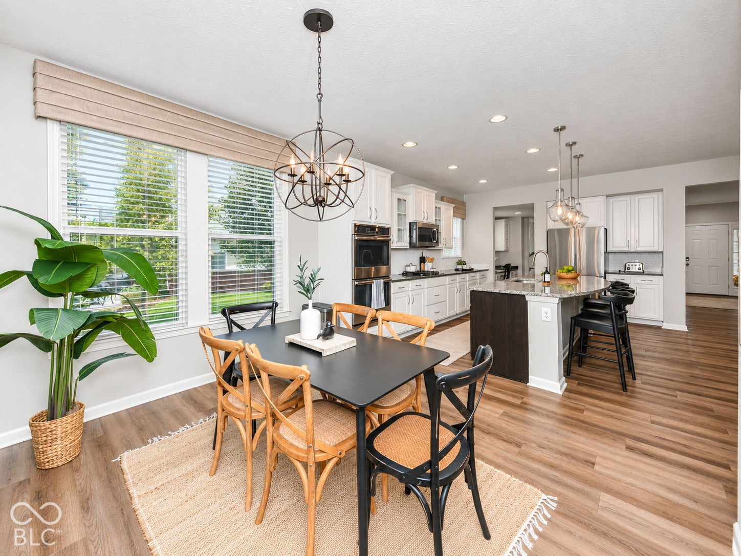Expansive wood-finish flooring, recessed lighting, and a modern kitchen island with pendant lighting