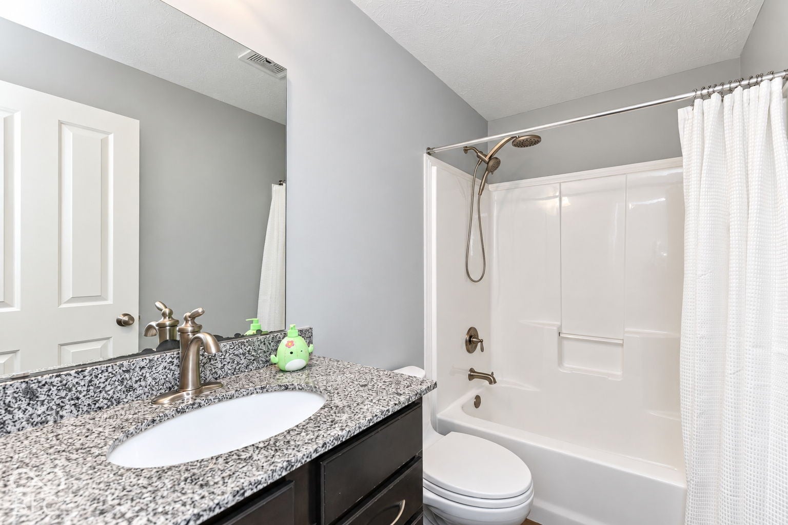 Bathroom featuring a single vanity with a granite countertop, undermount sink, and brushed nickel faucet