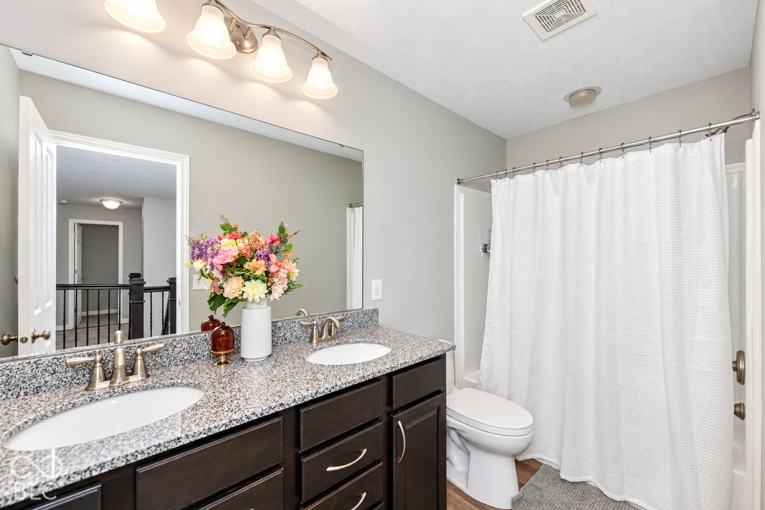 Double vanity with integrated sinks, speckled countertop, and dark wood-finish cabinetry