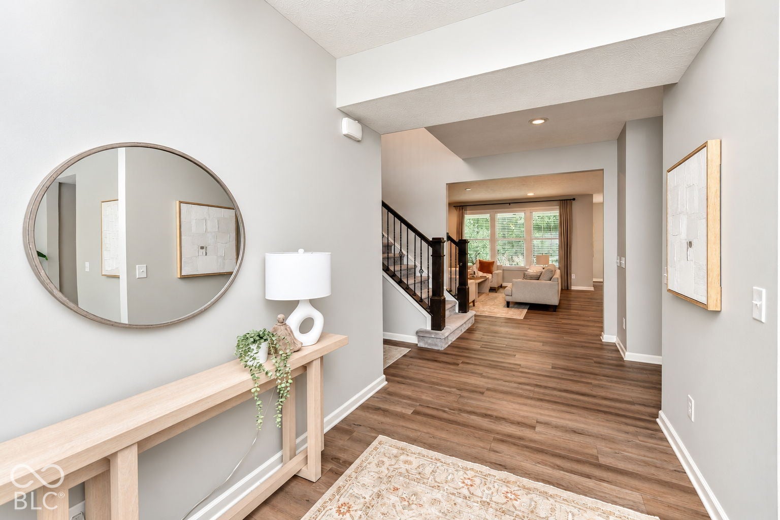 Wood-finish flooring throughout, framed openings, and a staircase with dark balusters and light-colored treads