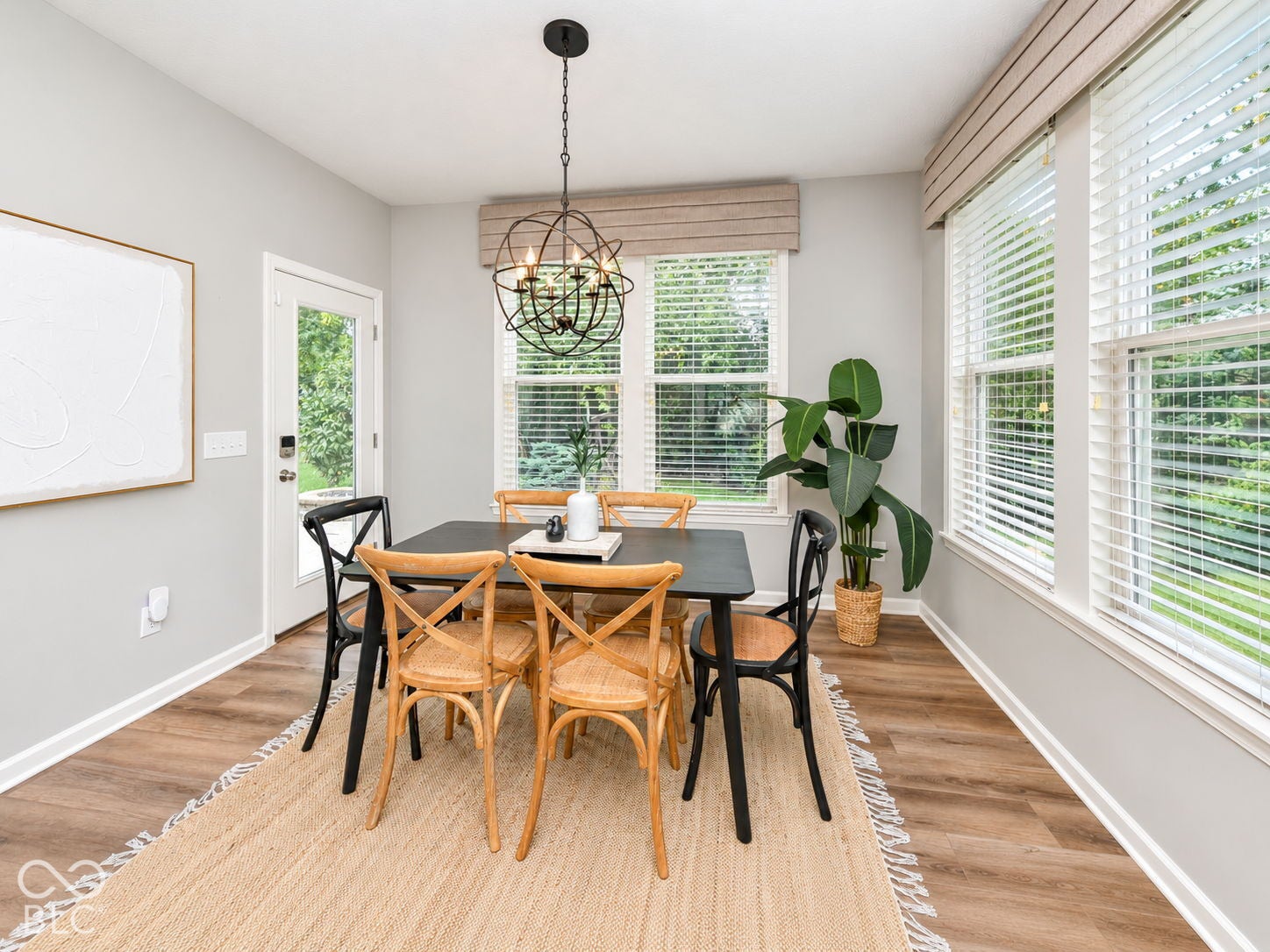 Wood-finish flooring, multiple windows with blinds, ceiling-mounted light fixture, and a glass-paneled door